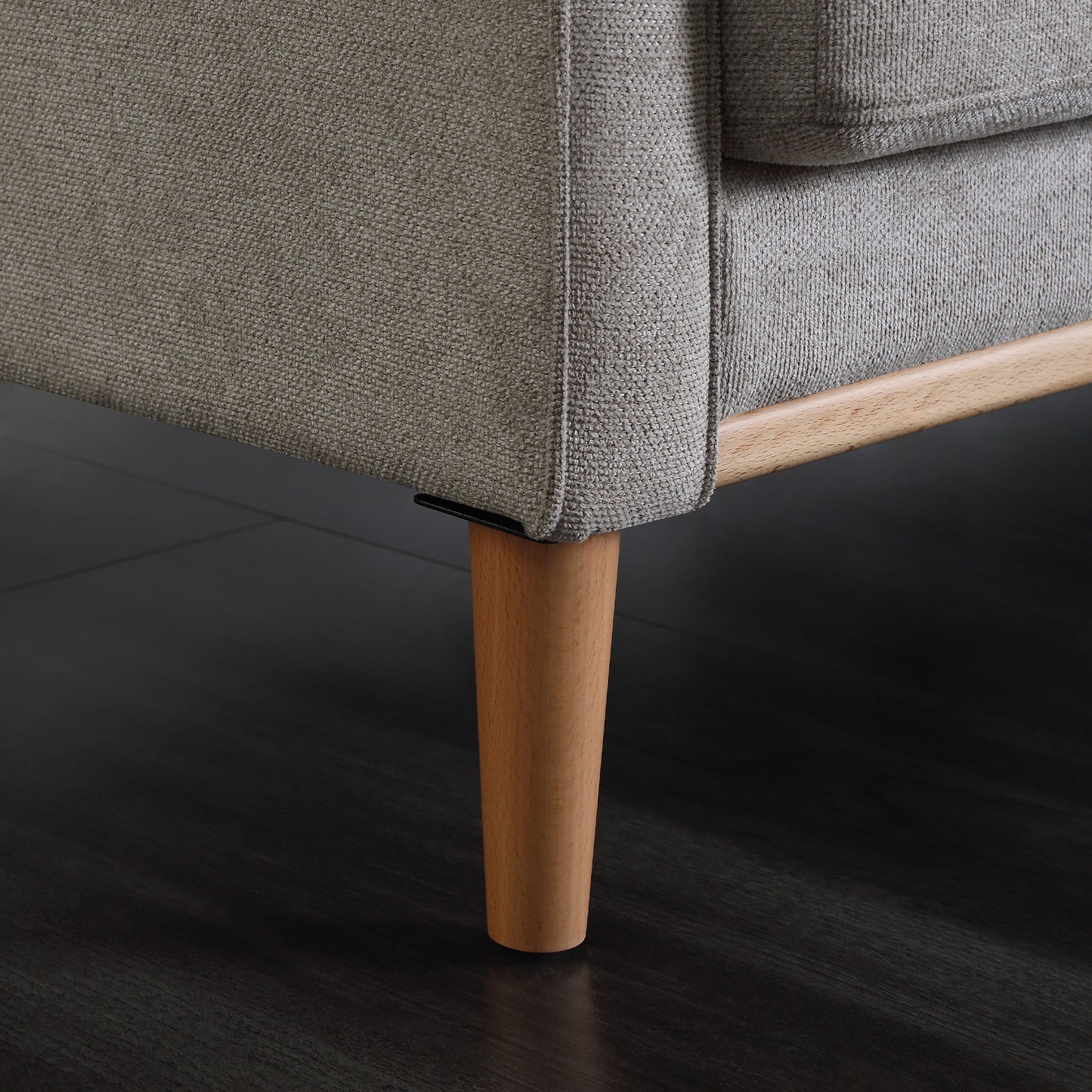 Textured grey fabric sofa corner with tapered natural wood legs on dark floor