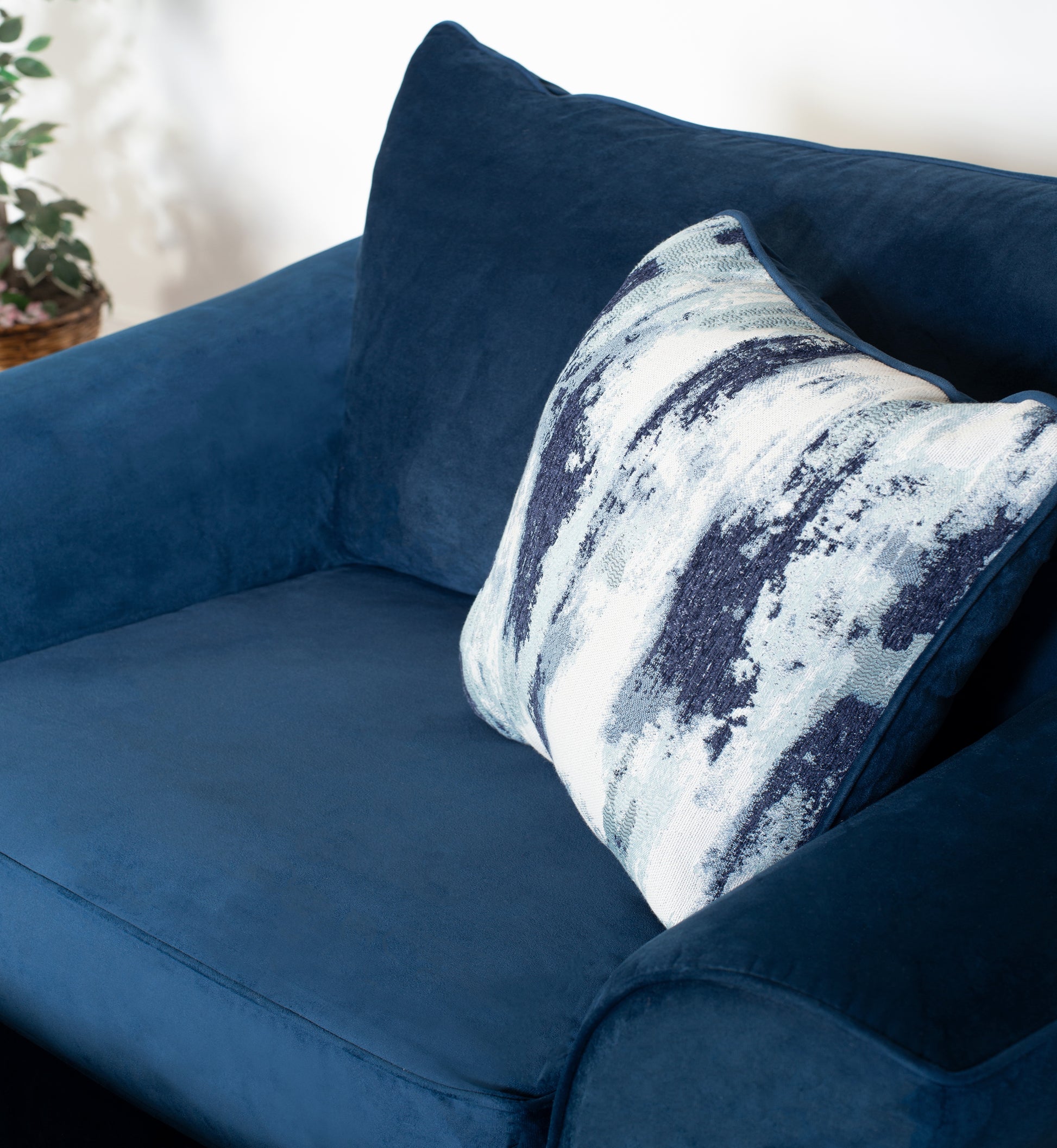 Deep blue velvet armchair with a modern abstract patterned throw pillow