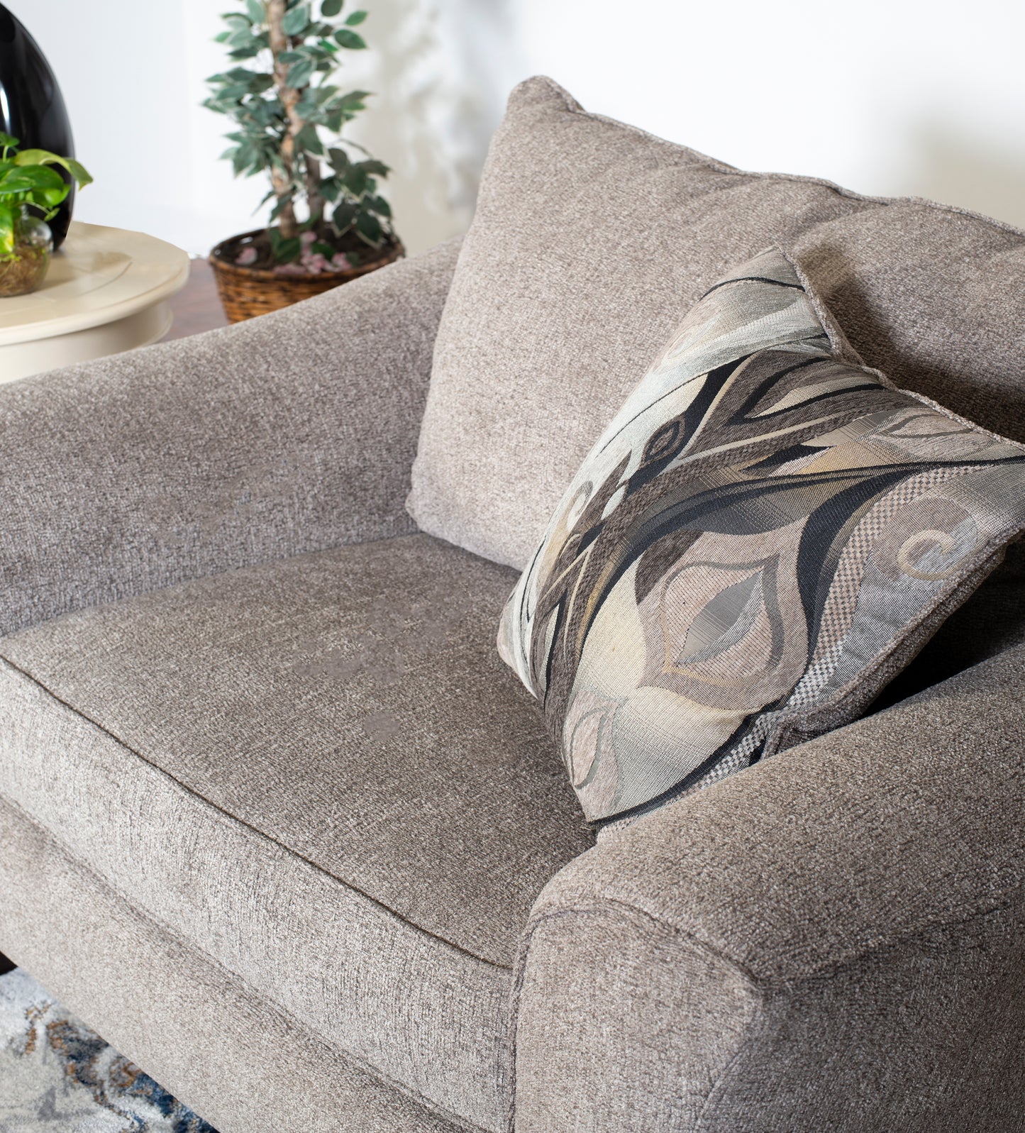 Taupe textured armchair with a decorative abstract patterned throw pillow