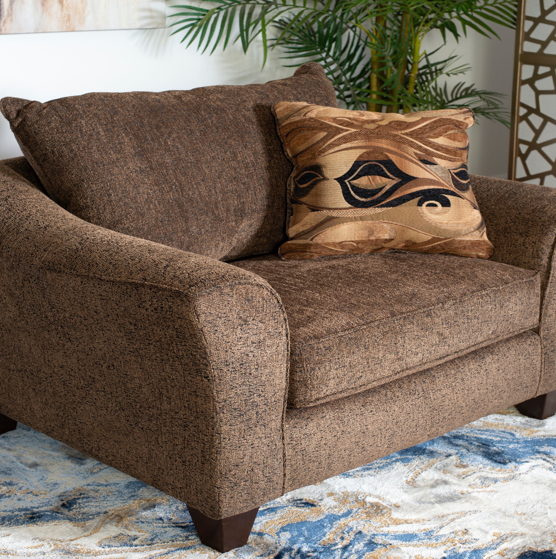 Comfortable brown textured fabric armchair with abstract patterned throw pillow
