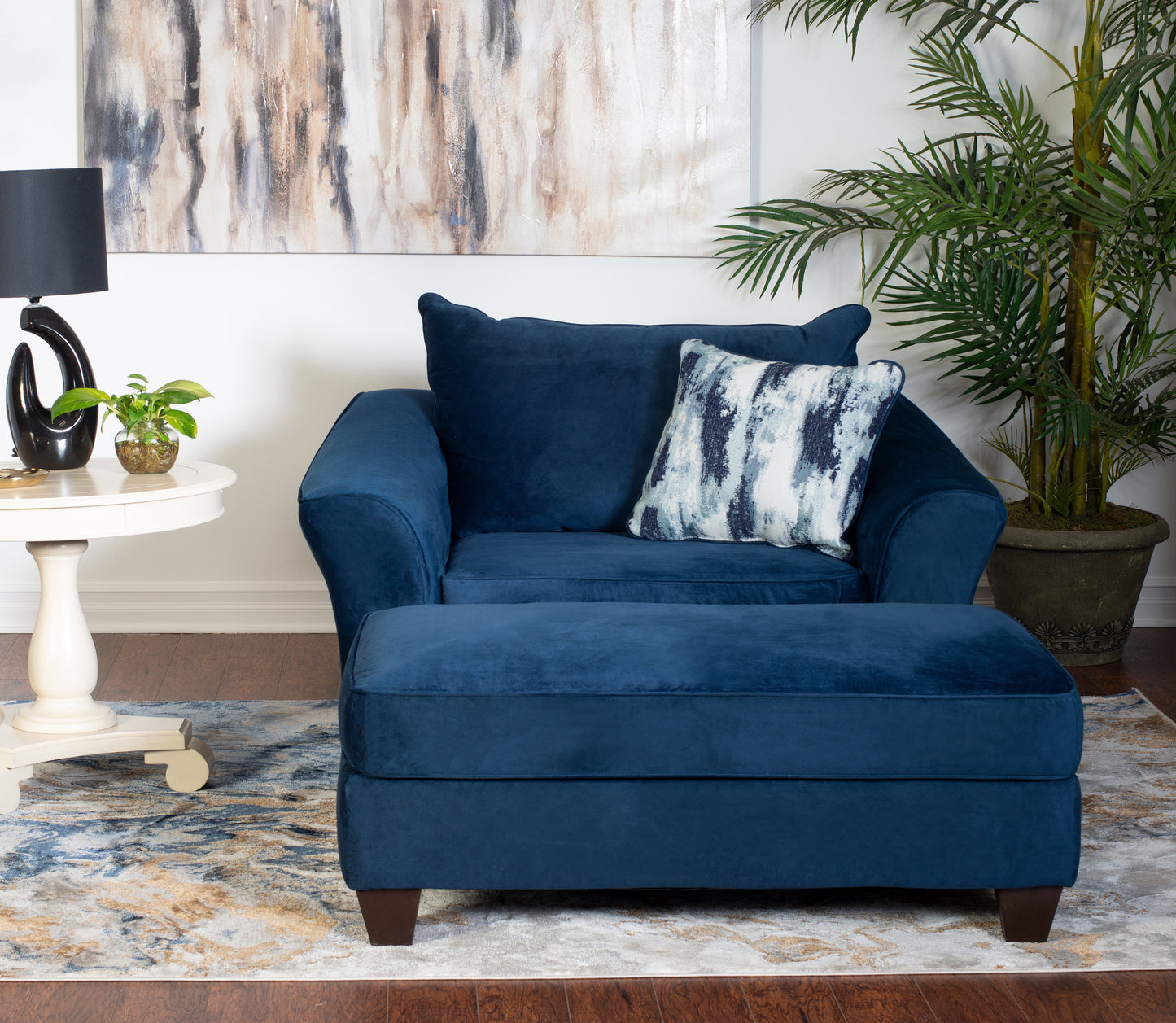 Plush navy blue velvet armchair with matching ottoman and abstract patterned throw pillow
