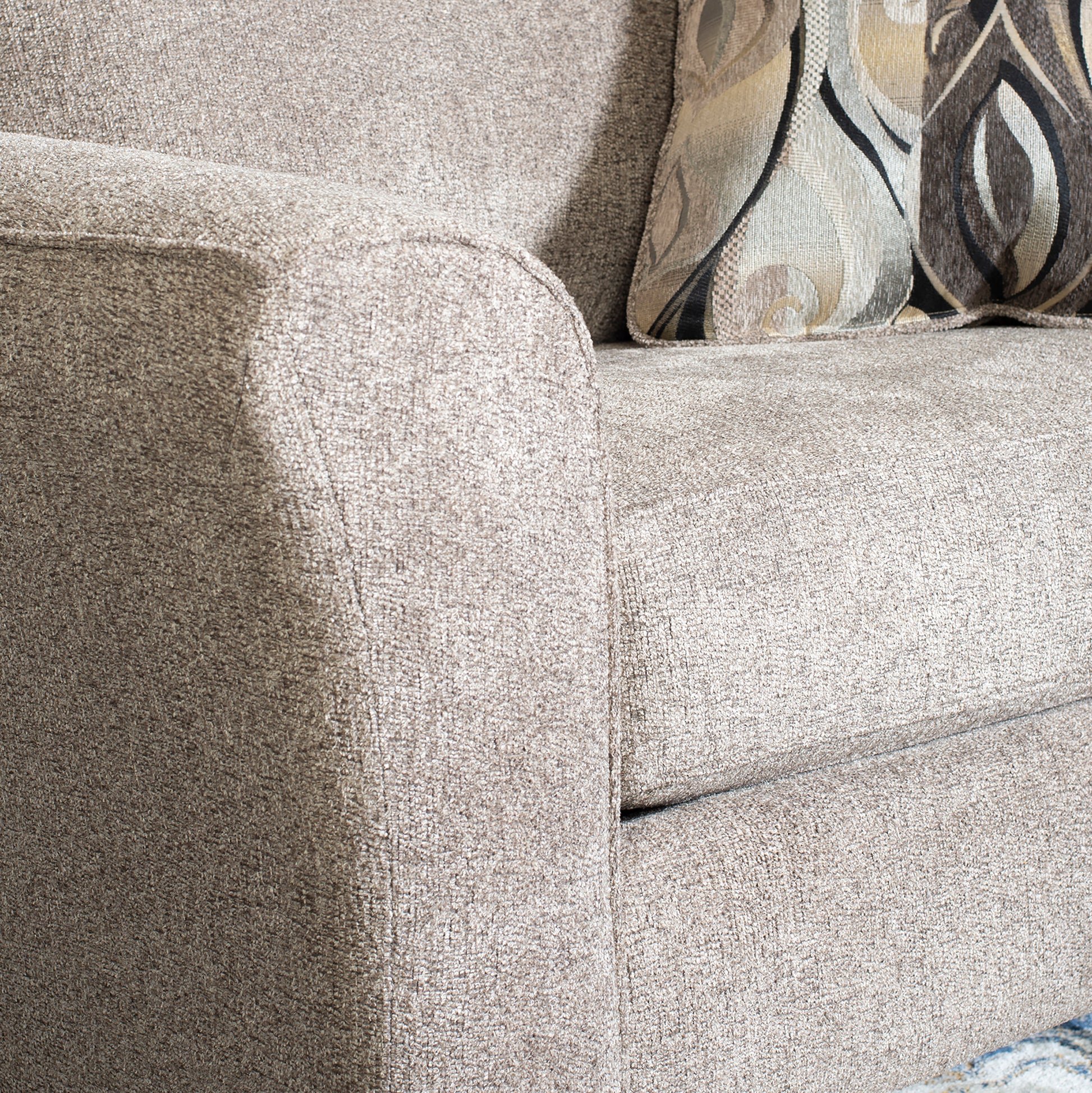 Taupe textured fabric sofa armrest with decorative abstract pattern pillows