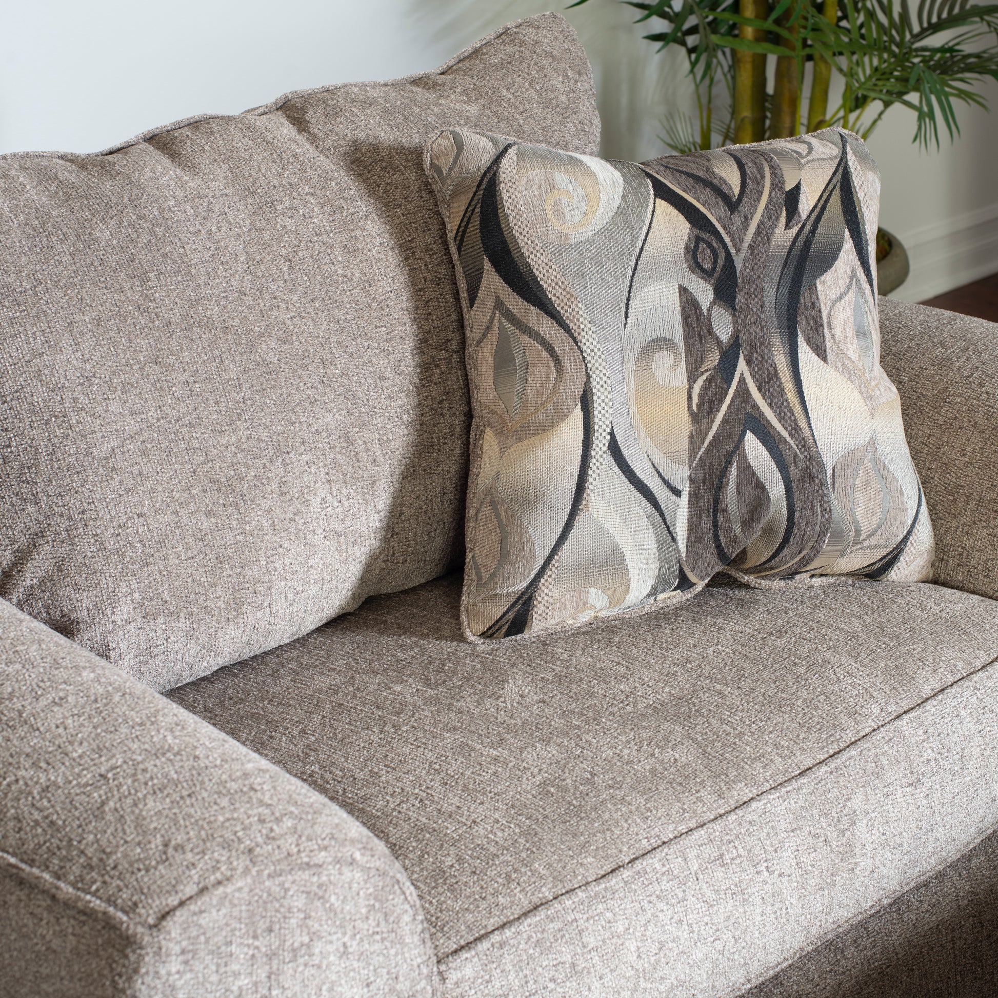Closeup of a plush textured beige sofa cushion with a patterned accent pillow