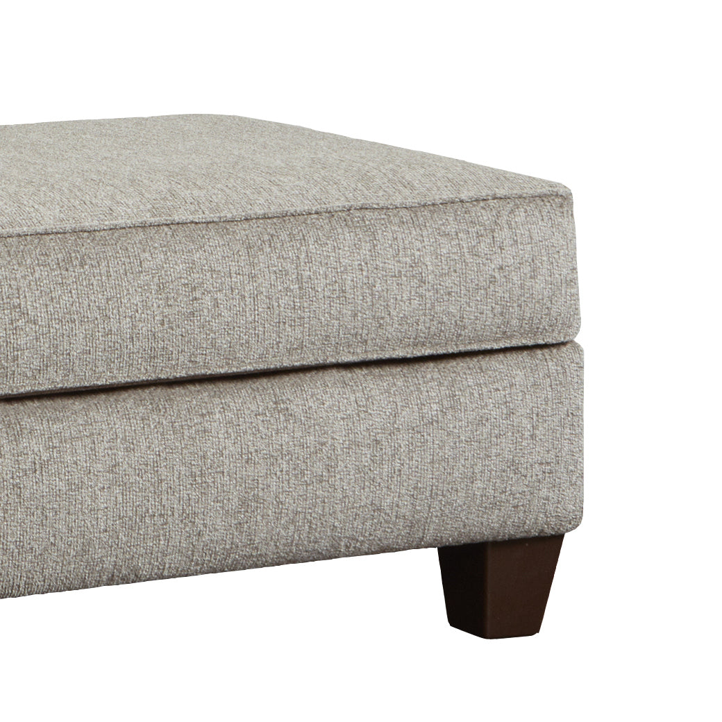 Beige upholstered ottoman with tailored stitching and dark wooden feet