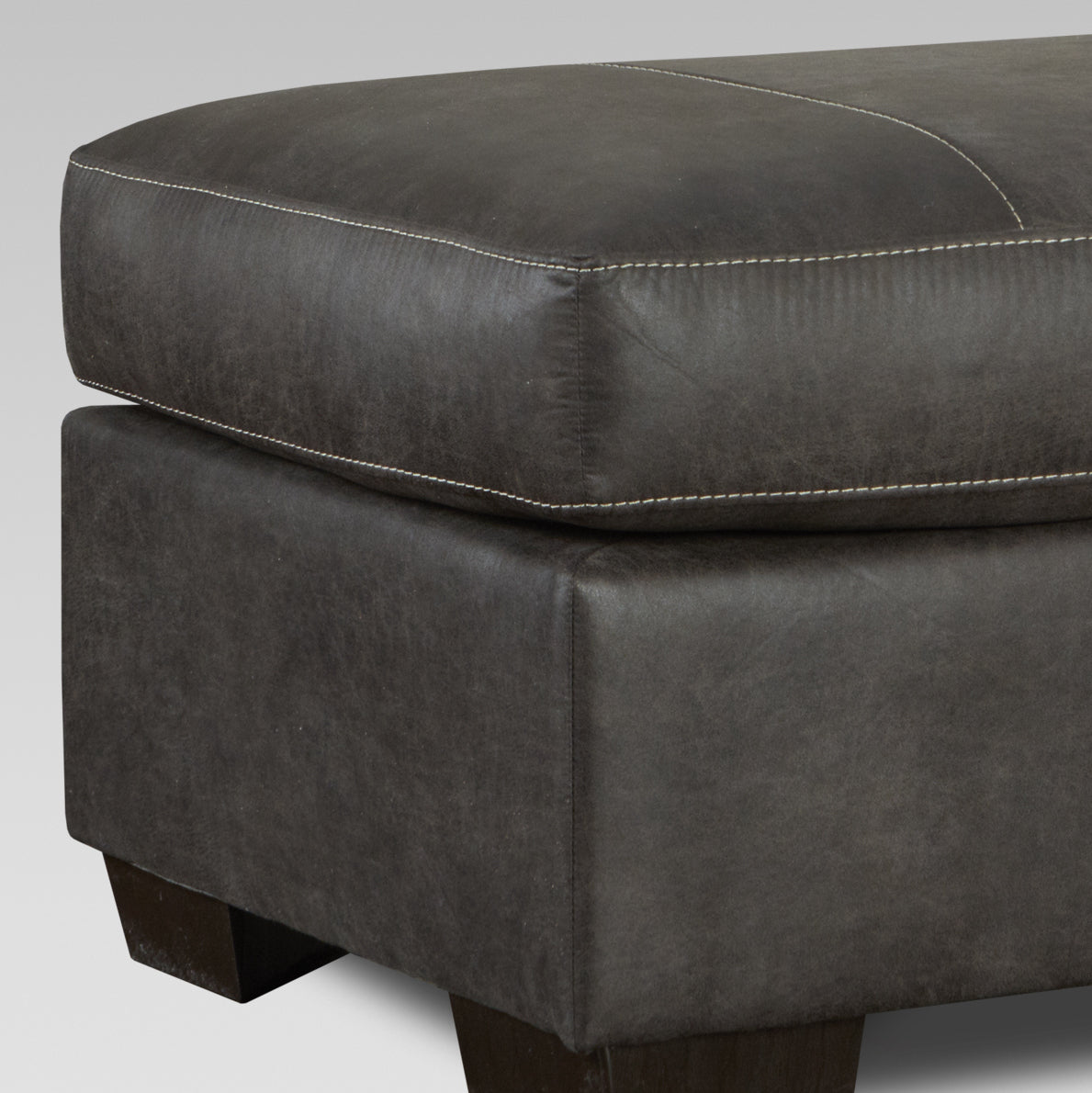 Dark gray leather ottoman with white contrast stitching and dark wood legs