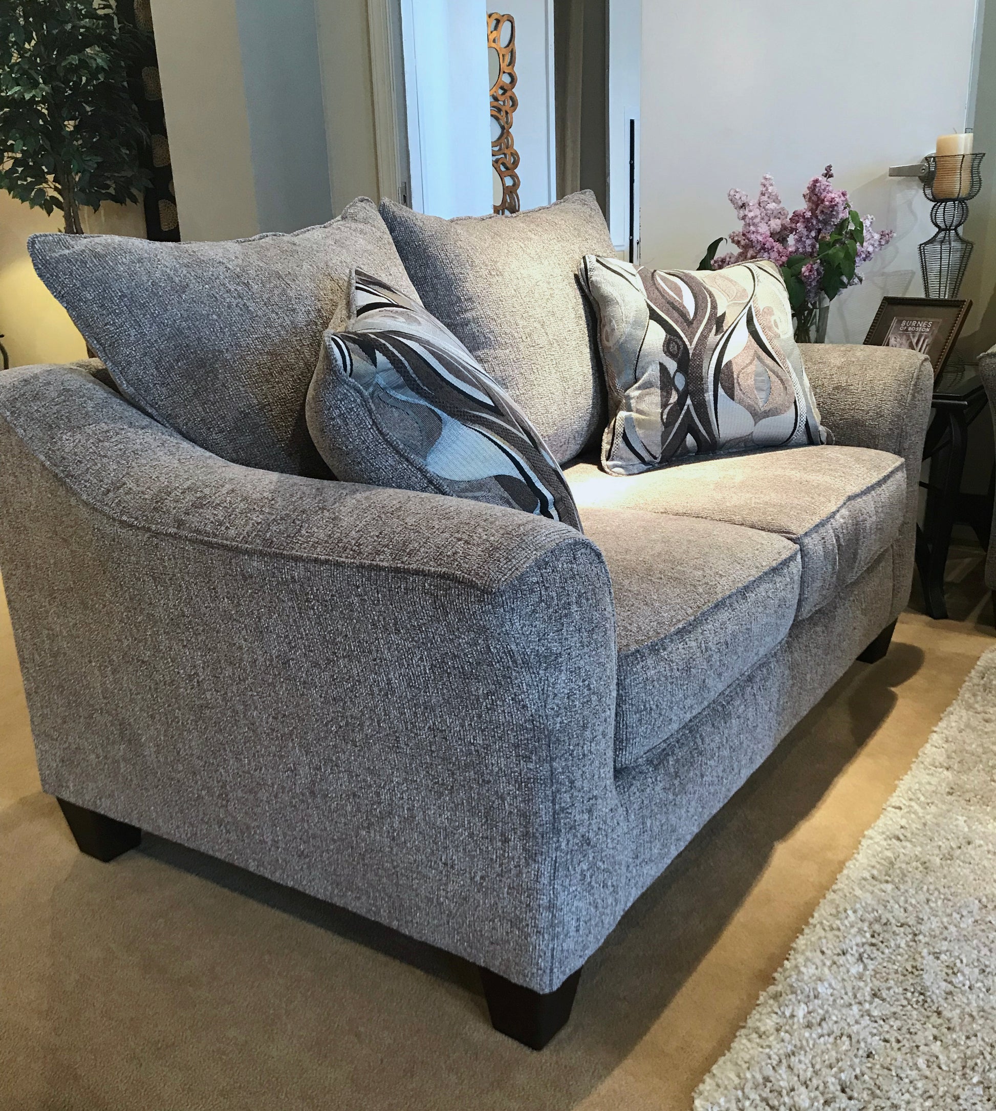 Grey fabric loveseat with patterned throw pillows and modern design