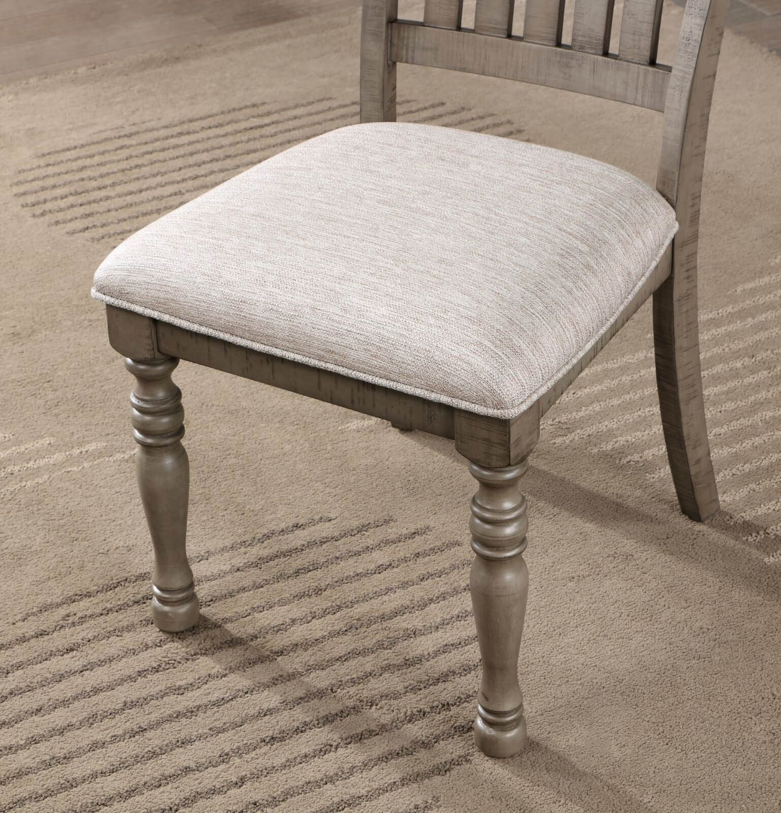Rustic grey wooden dining chair with light beige upholstered seat and turned legs
