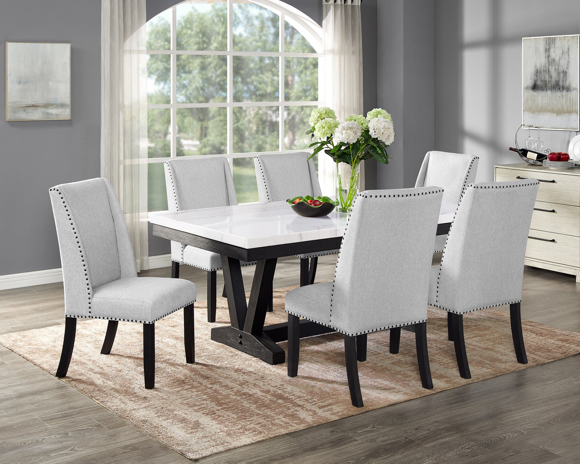 Elegant light gray upholstered dining chairs with nailhead trim paired with a marblelook dining table