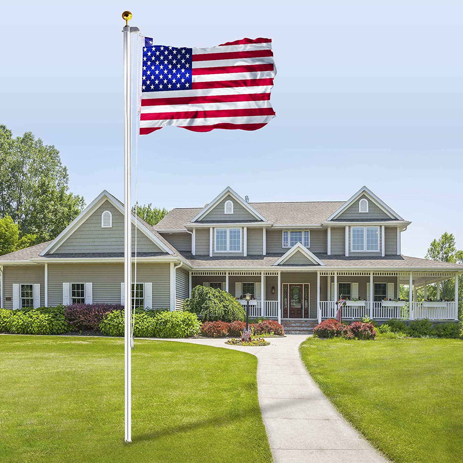 American flag proudly waving on a white flagpole in front of a suburban home