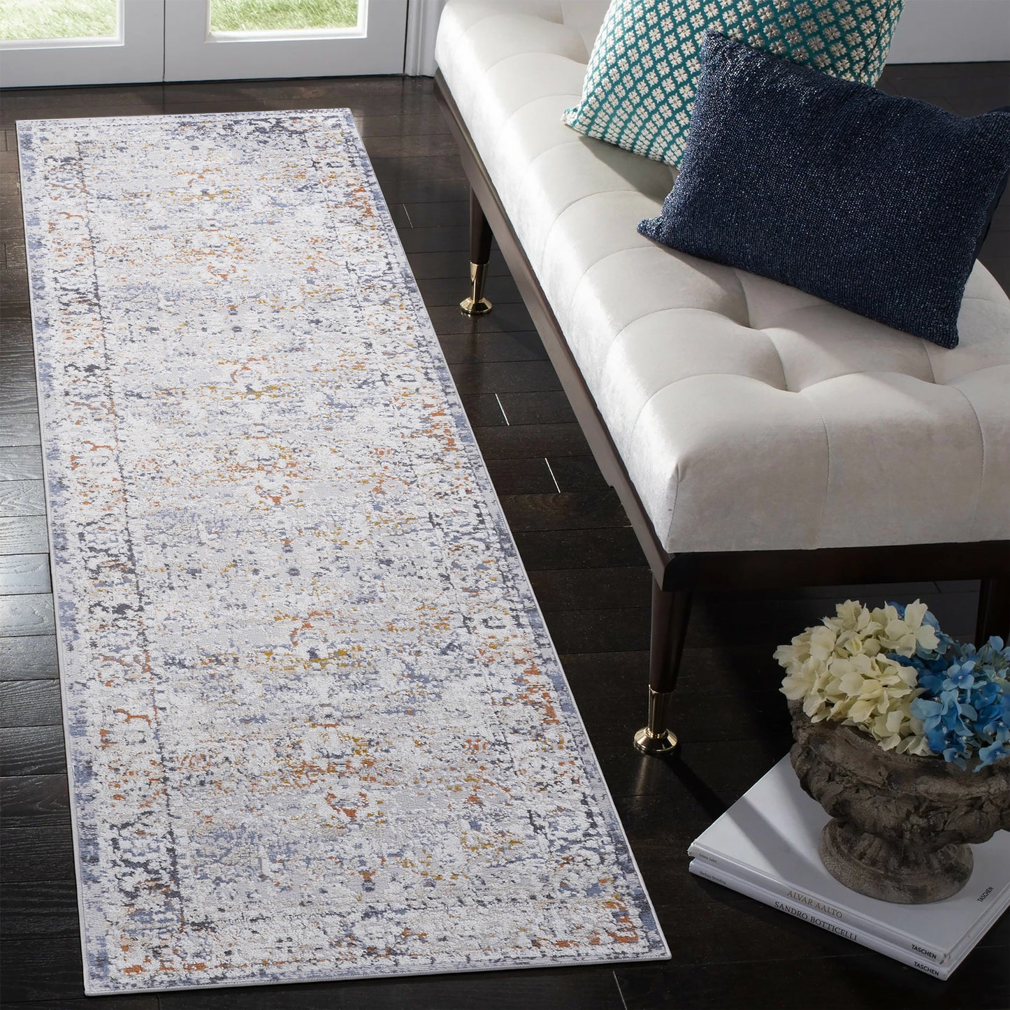 Distressed abstract runner rug with grey blue and orange hues on a dark wood floor