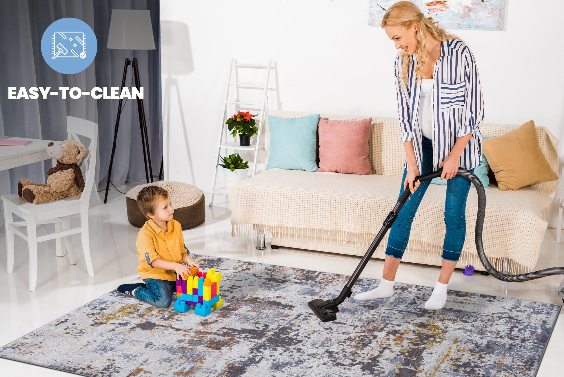Gray and yellow abstract print area rug on white floor with woman vacuuming