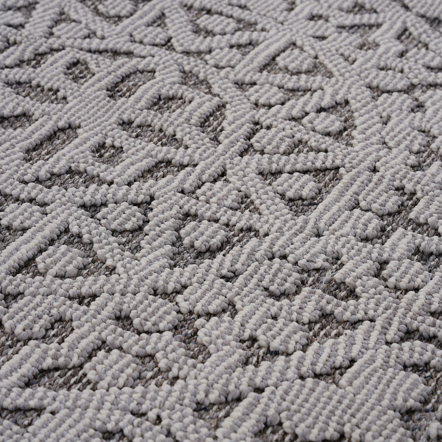 Closeup of a grey and white textured area rug with a geometric pattern
