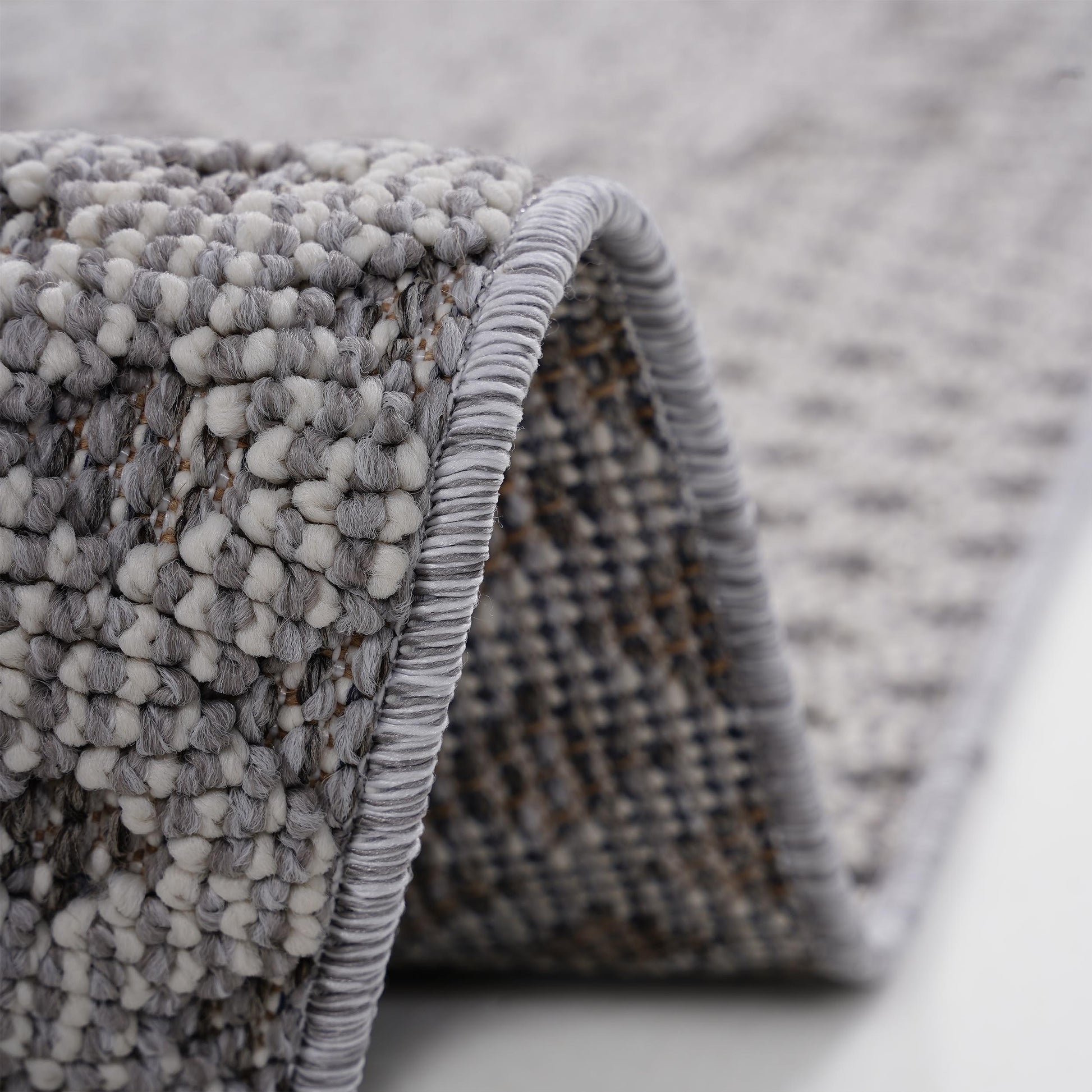 Closeup texture of a grey and white shag rug showing looped yarn construction