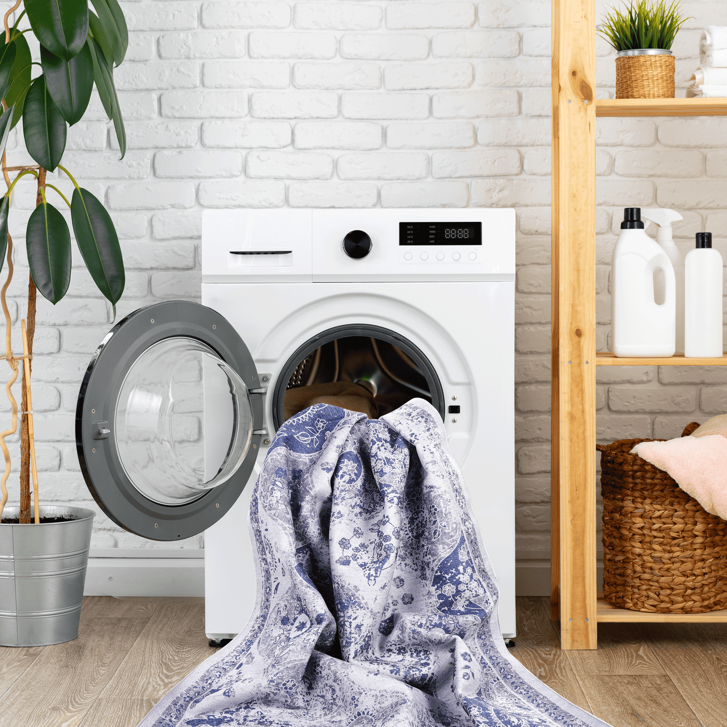 Blue and white ornate patterned rug being loaded into a white washing machine for cleaning