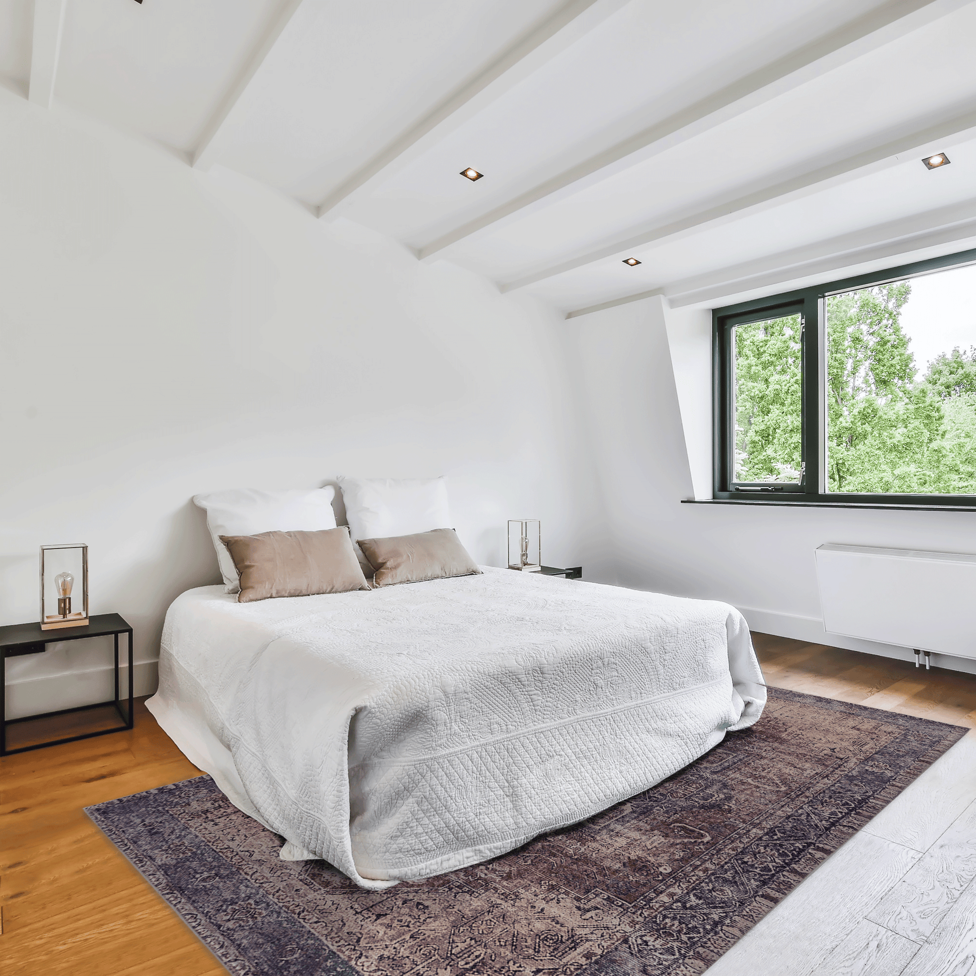 White quilted bedspread with beige accent pillows on wooden floor with vintage Persian rug