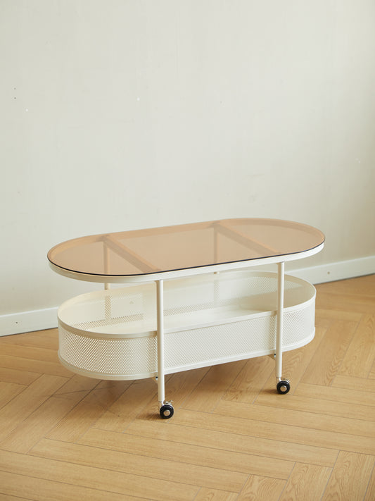 White oval metal coffee table with two shelves and amber glass top
