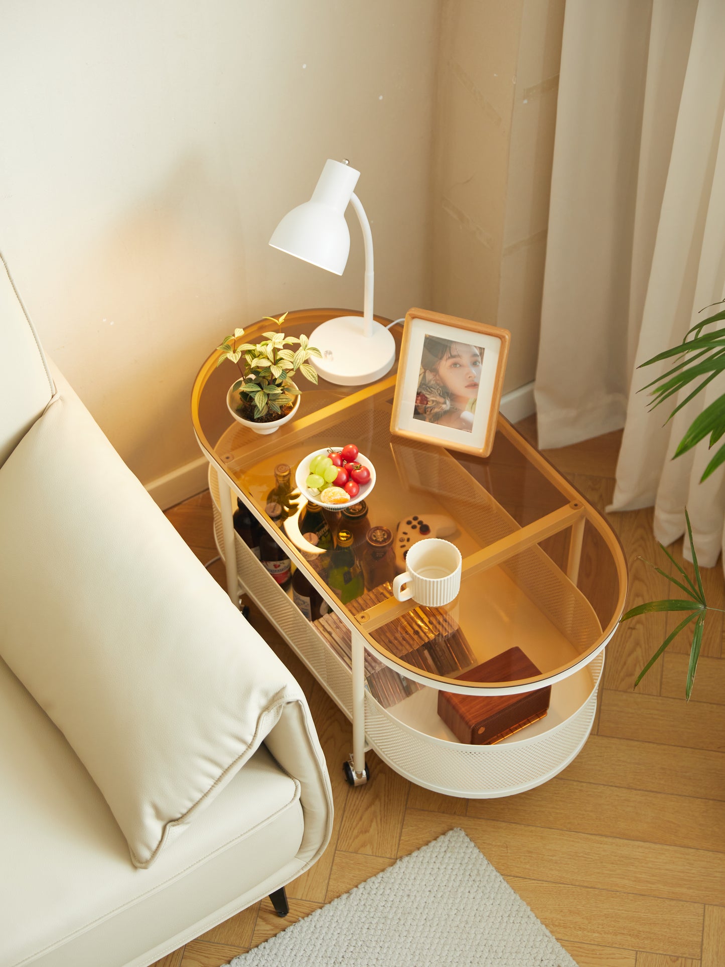 Modern glass top side table with white metal frame and wheels holding drinks and snacks