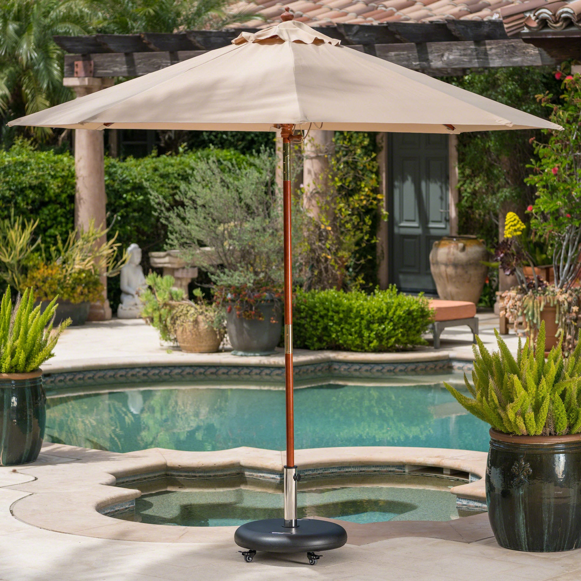 Beige patio umbrella with wooden pole and black wheeled base ideal for poolside shade