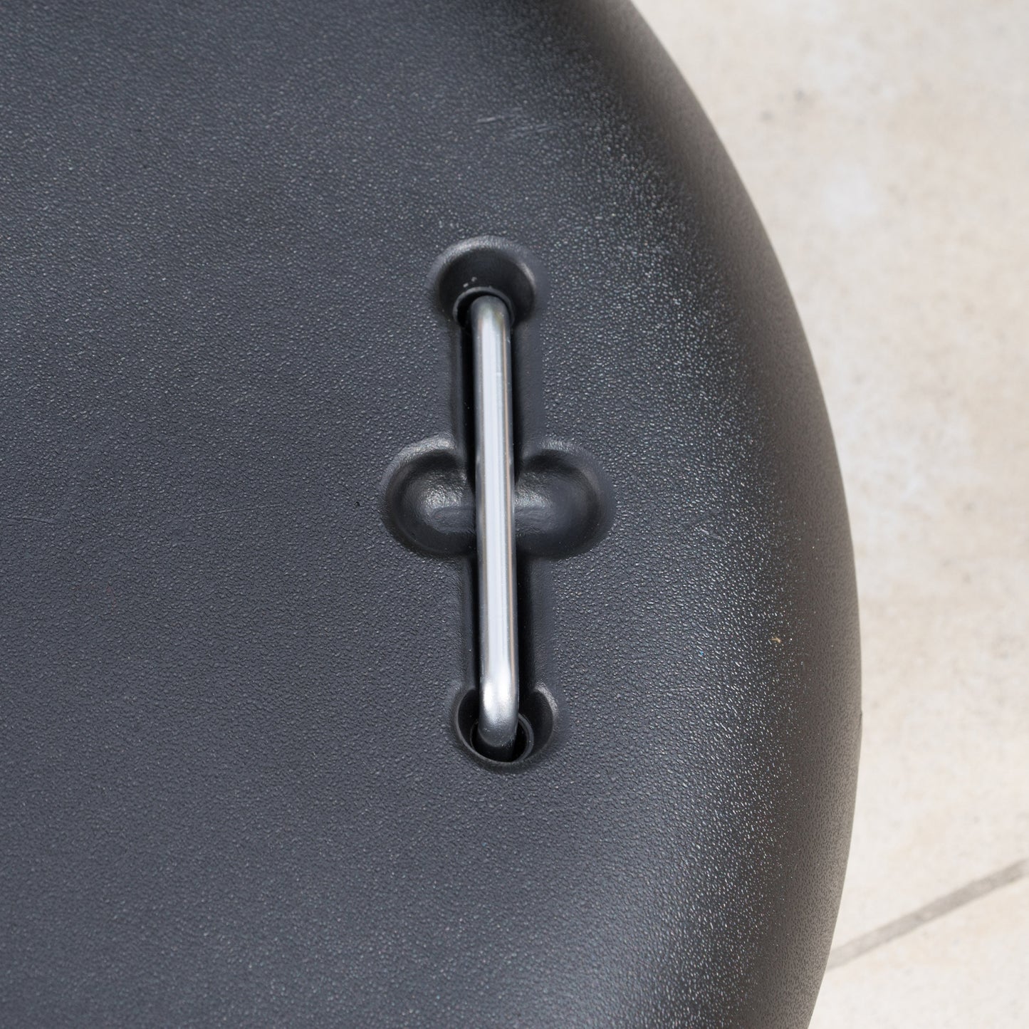 Closeup of textured black plastic with a silver metal pin for strap attachment