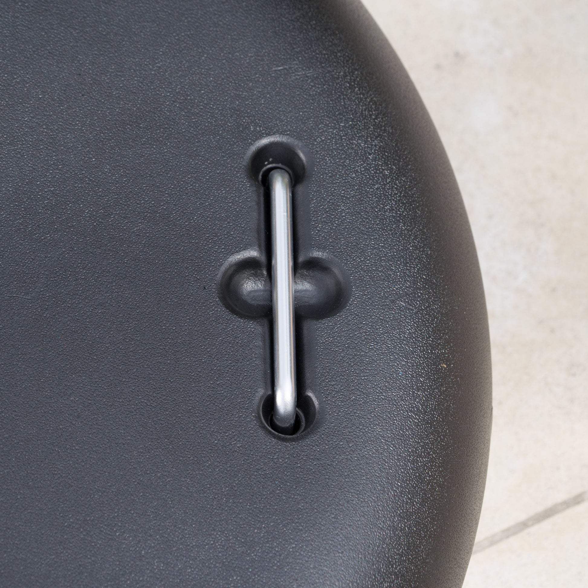 Closeup of textured black plastic with a silver metal pin for strap attachment
