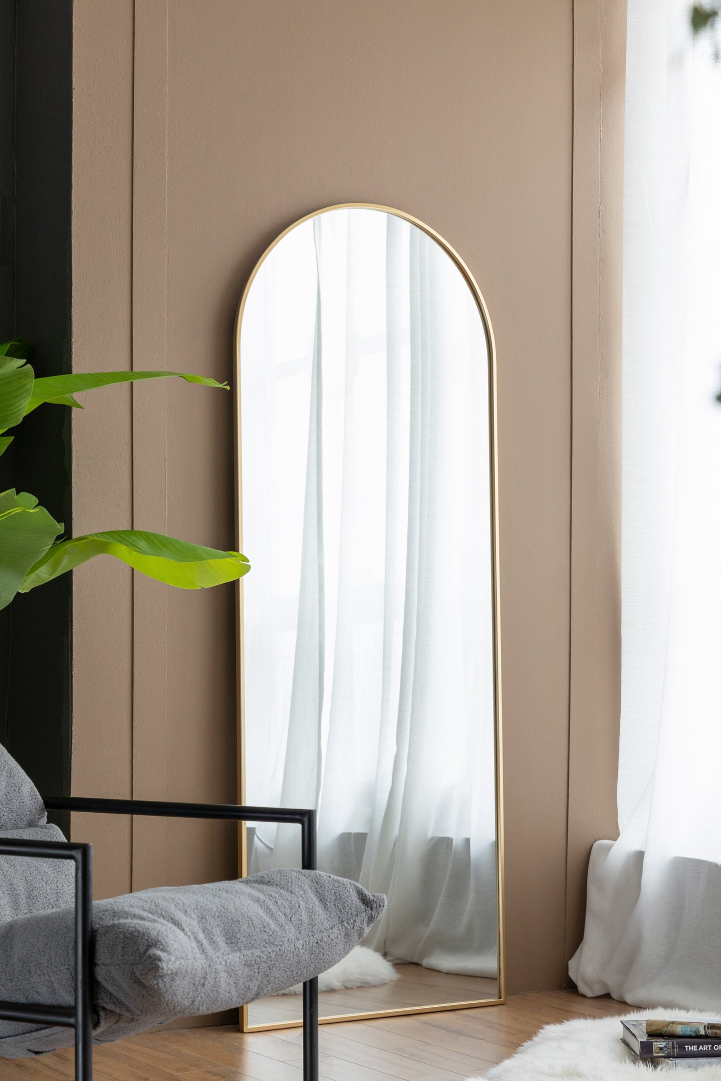 Tall arched gold mirror with a sleek modern design perfect for fullbody dressing