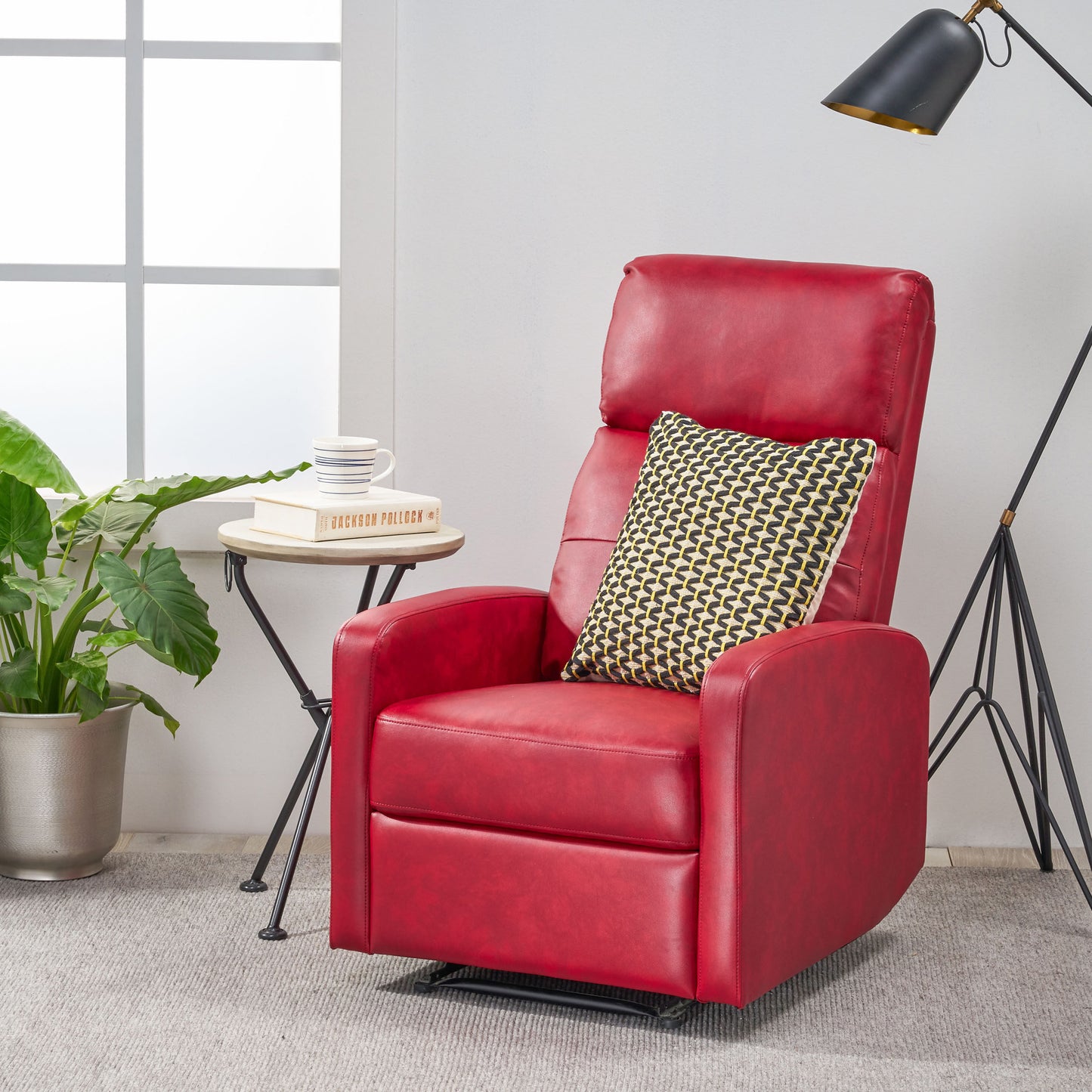 Red leather recliner with decorative pillow and metal side table