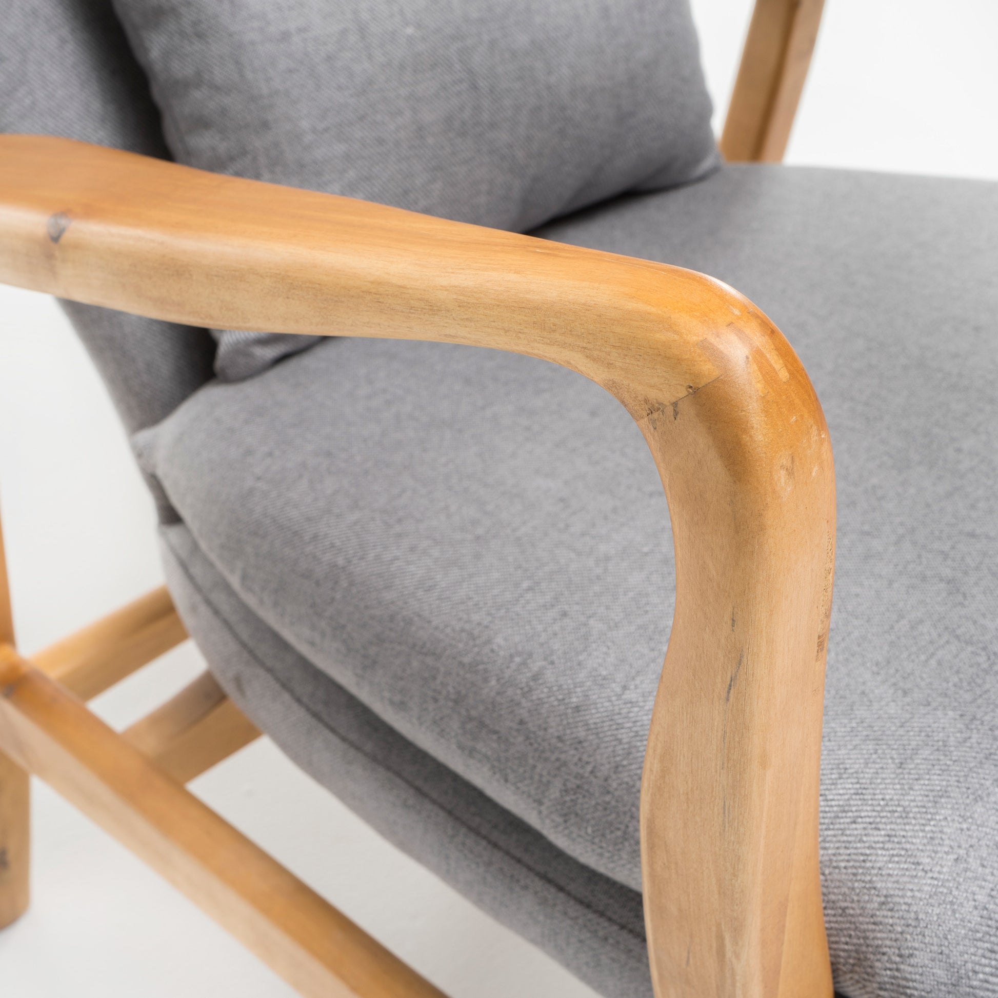 Closeup of a grey upholstered accent chair with smooth wooden armrests