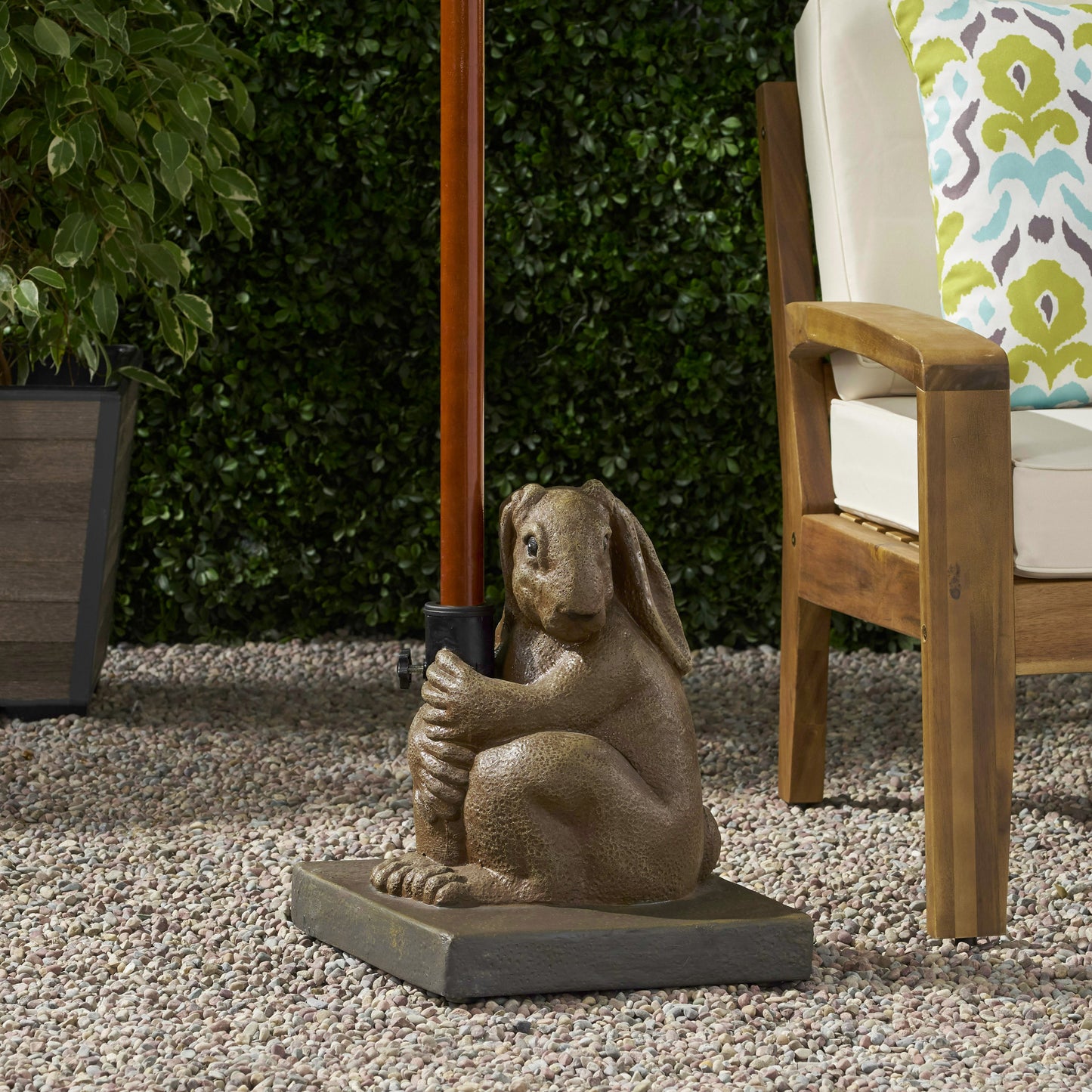 Brown resin bunny statue holding umbrella pole on patio