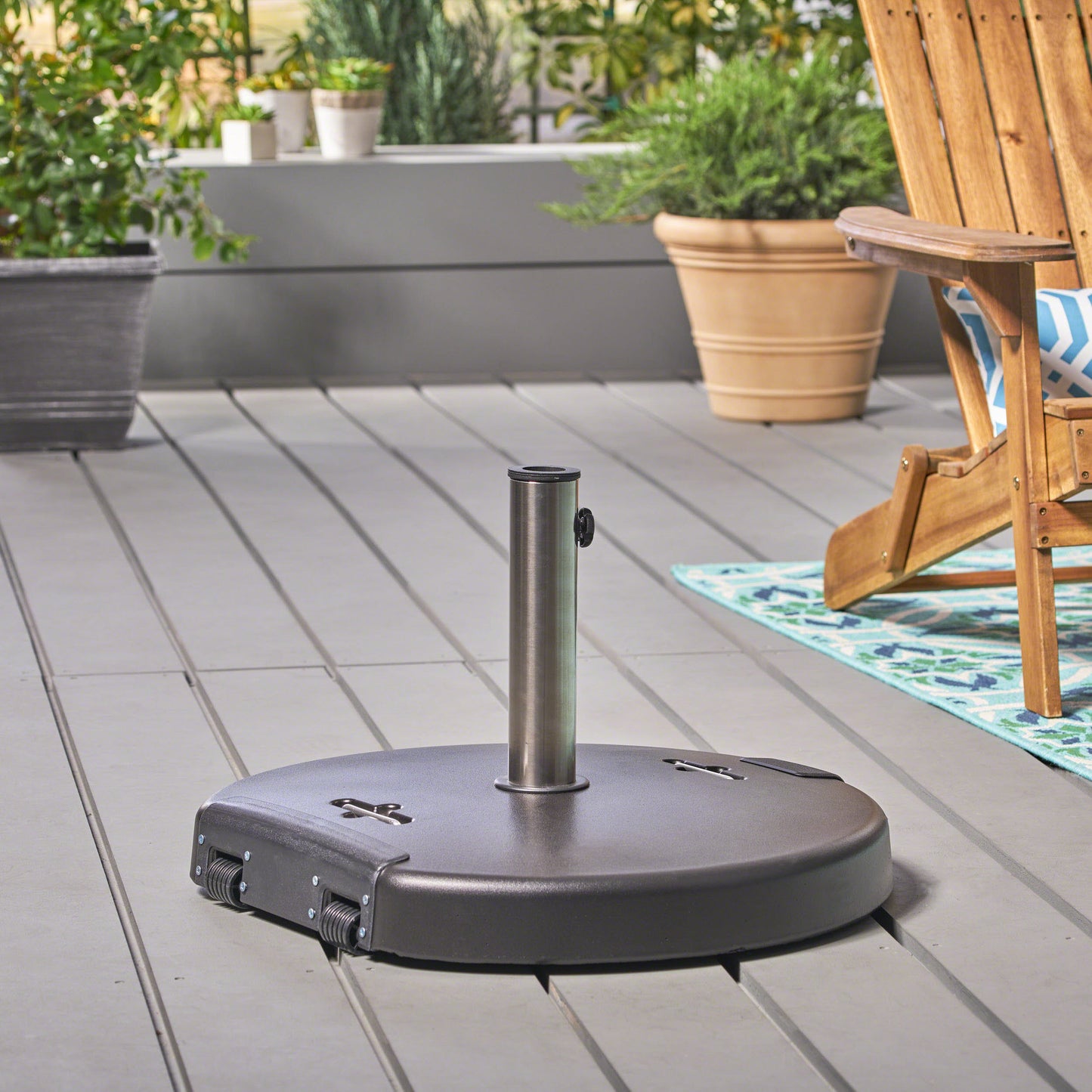 Dark gray wheeled patio umbrella base with silver pole on wooden deck