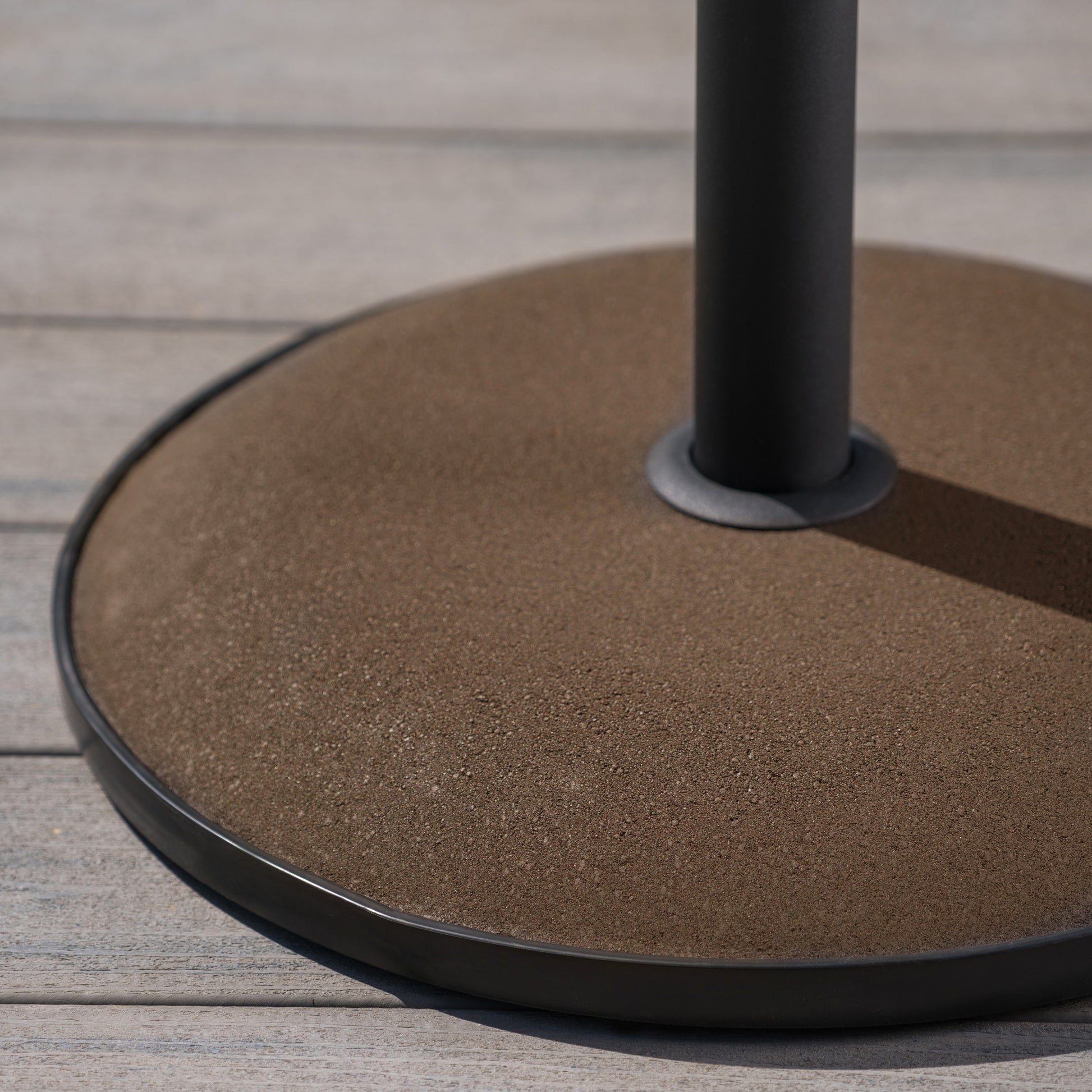 Round textured brown umbrella base with black metal pole and rim
