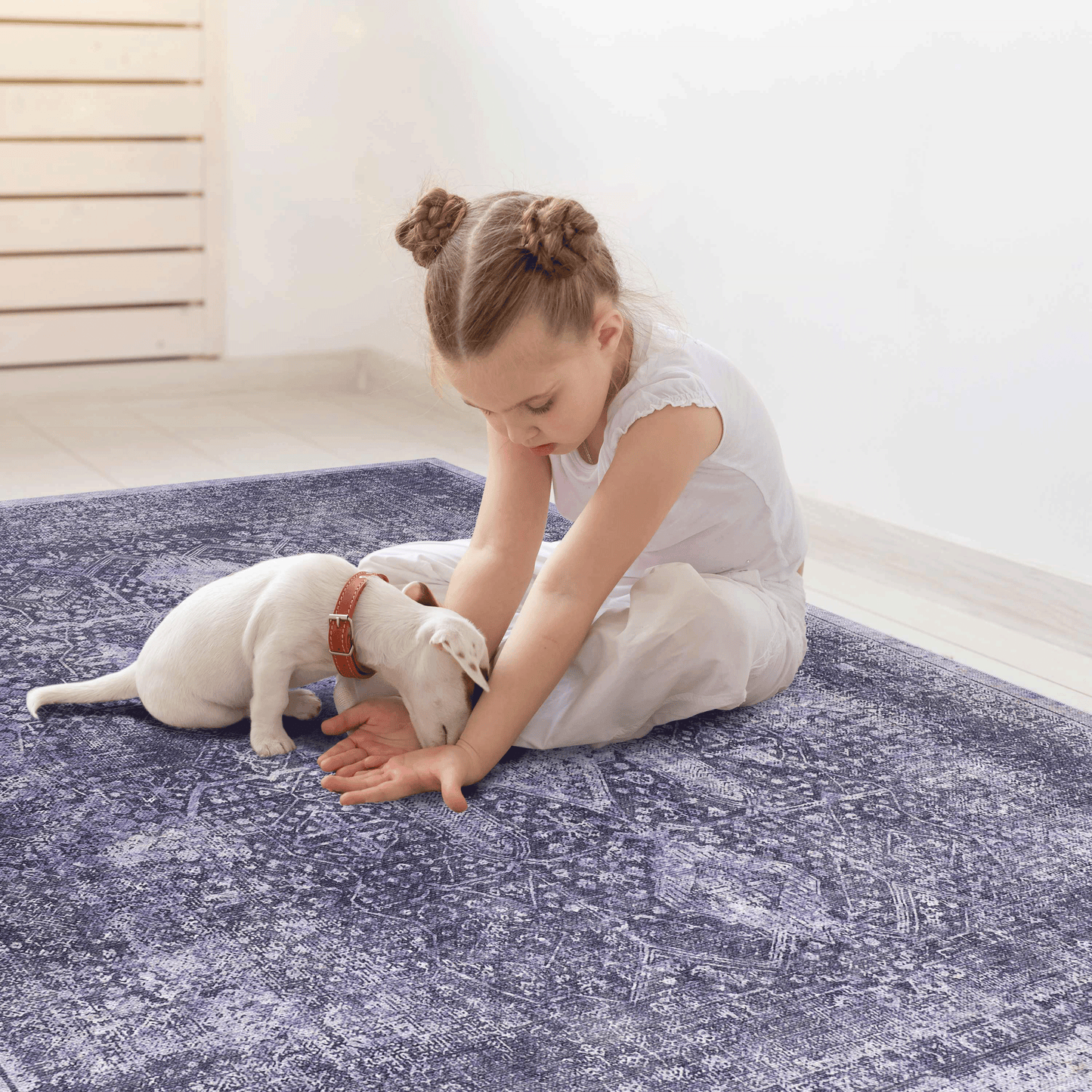 Girl with white puppy playing on a vintage oriental rug