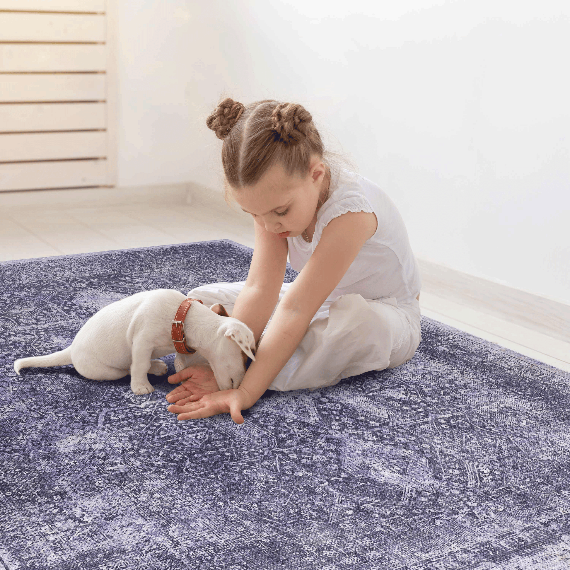 Girl with white puppy playing on a vintage oriental rug