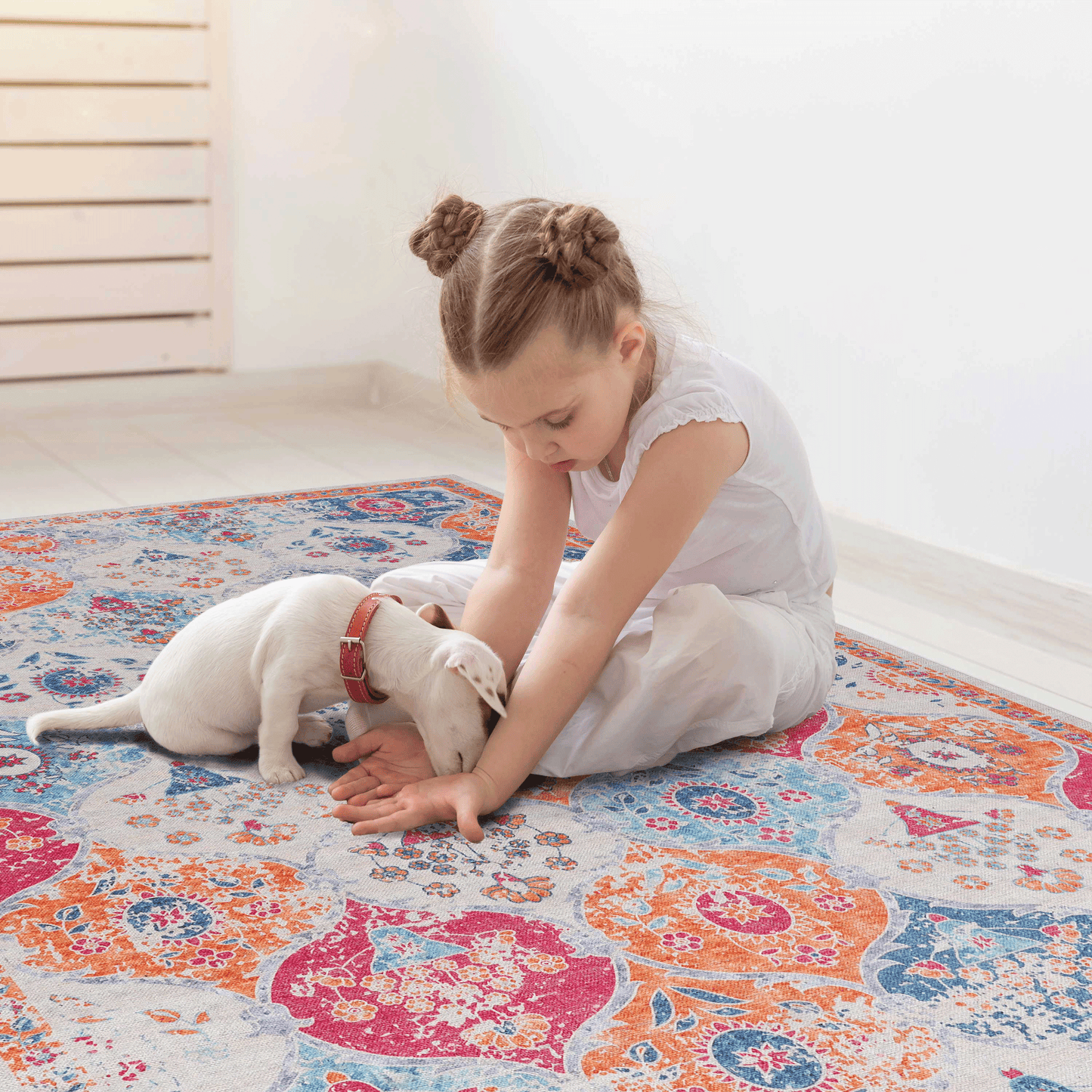 Distressed medallion area rug in orange blue and pink with a white puppy playing on it