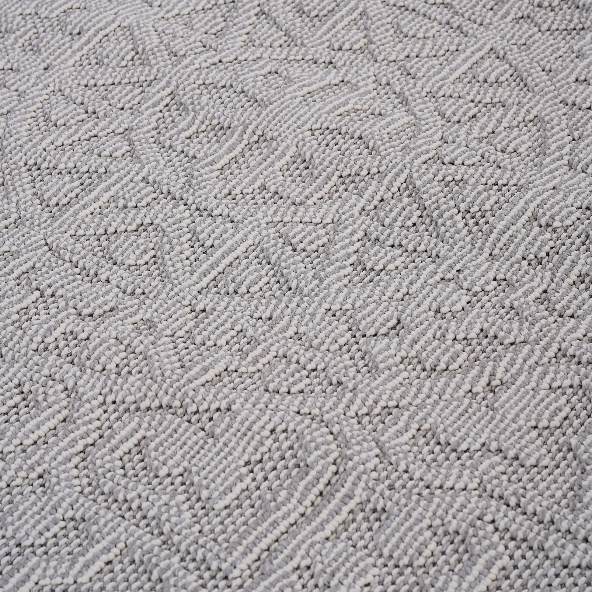 Closeup texture of a grey and white woven rug with a chevron pattern