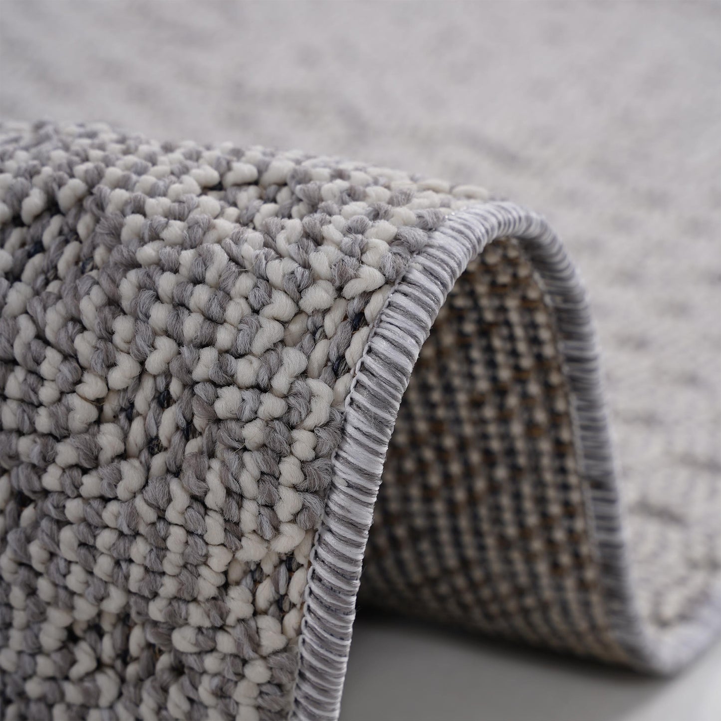 Closeup of a textured grey and white shag rug with a bound edge