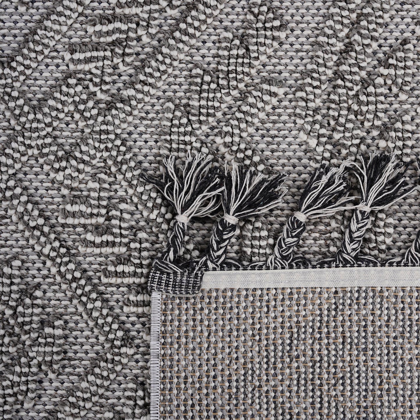 Textured geometric rug in black white and gray with braided tassels