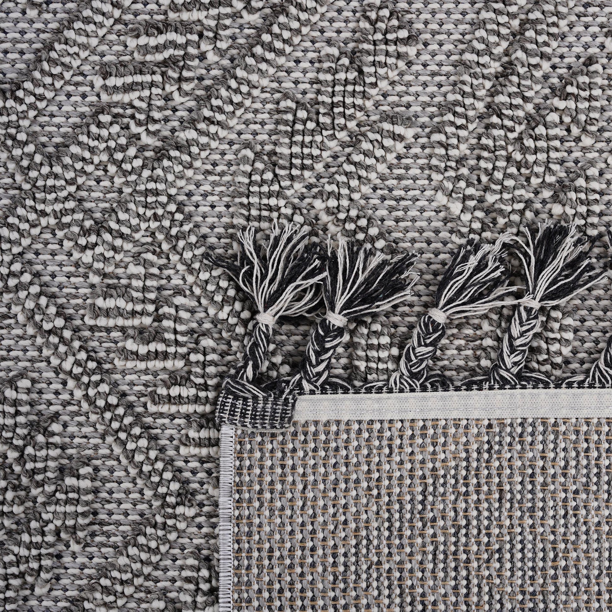 Textured geometric rug in black white and gray with braided tassels