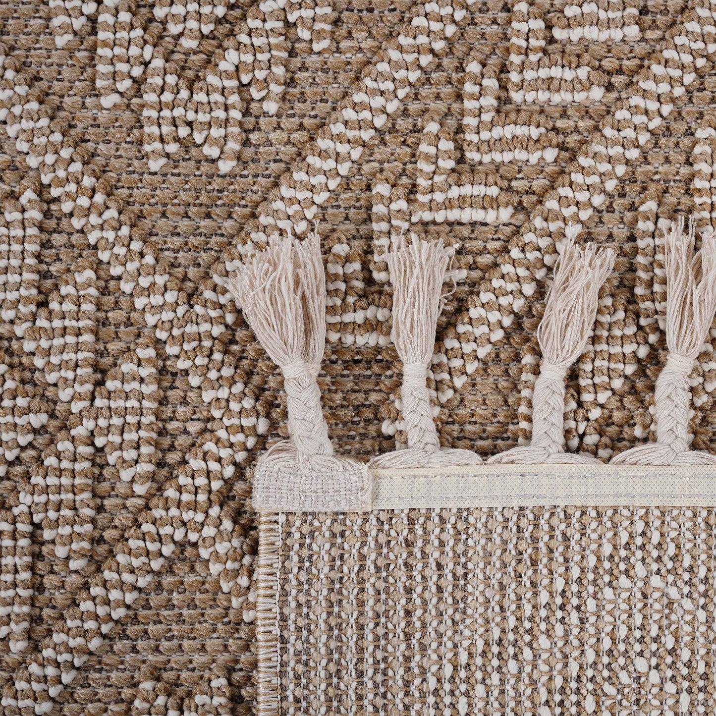 Closeup of a textured brown and cream geometric rug with tasseled edges perfect for adding warmth