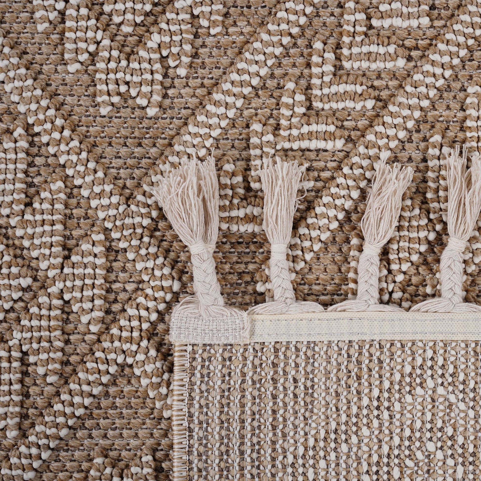 Closeup of a textured brown and cream geometric rug with tasseled edges perfect for adding warmth