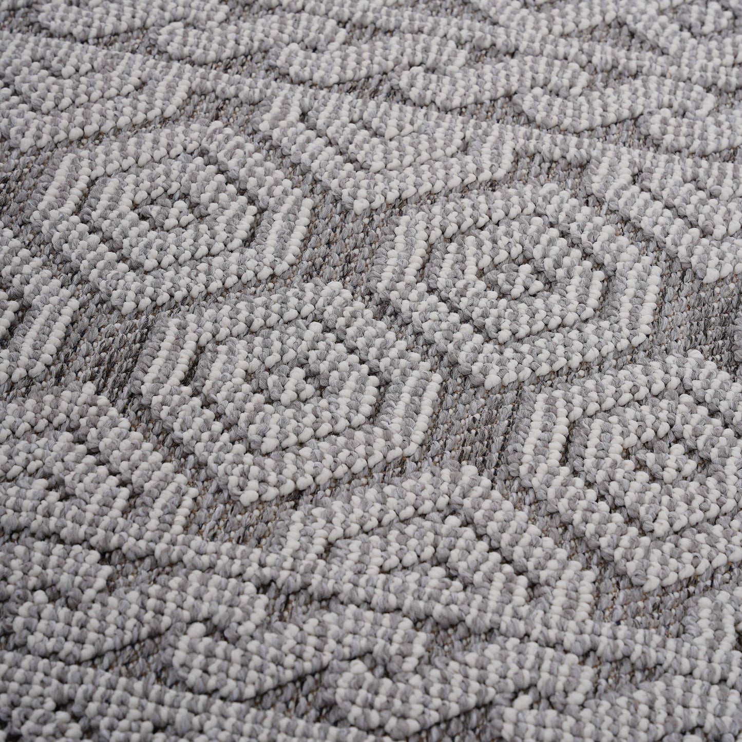 Closeup of a textured grey and white woven rug with a geometric pattern perfect for modern homes