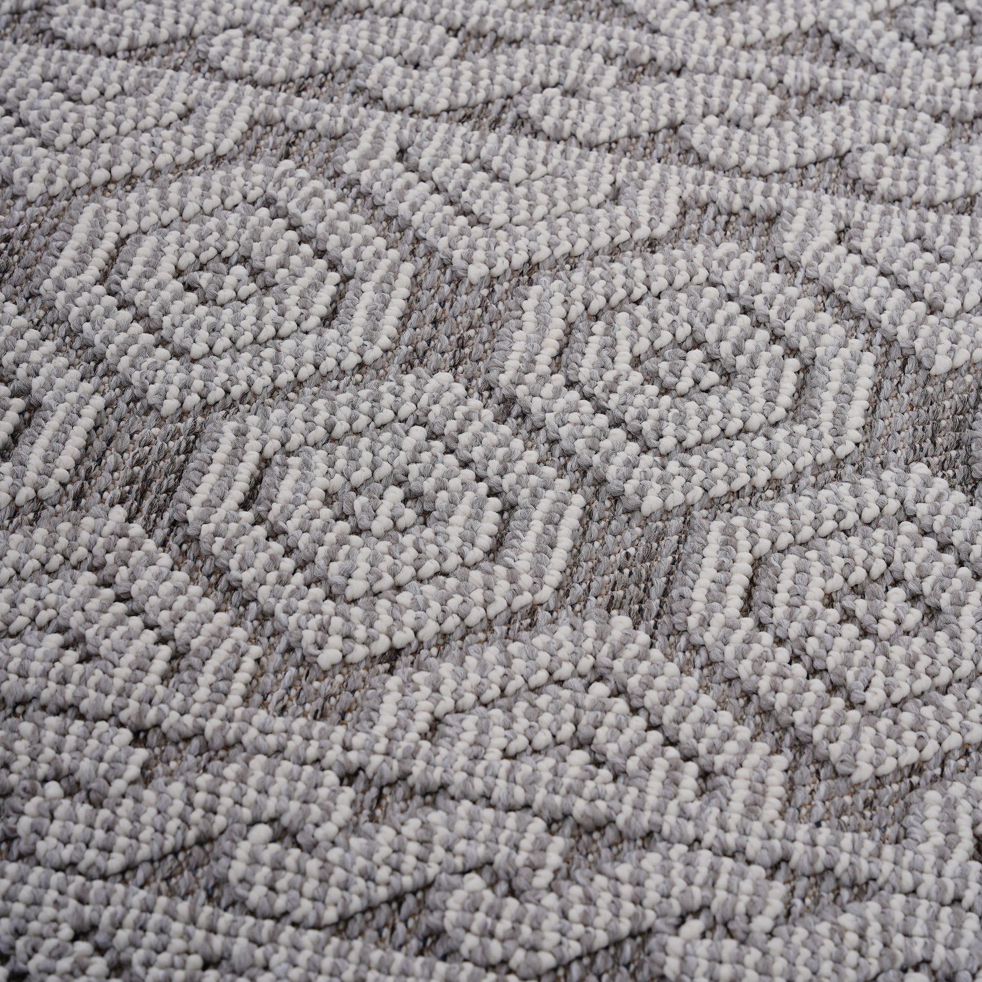 Closeup of a textured grey and white woven rug with a geometric pattern perfect for modern homes