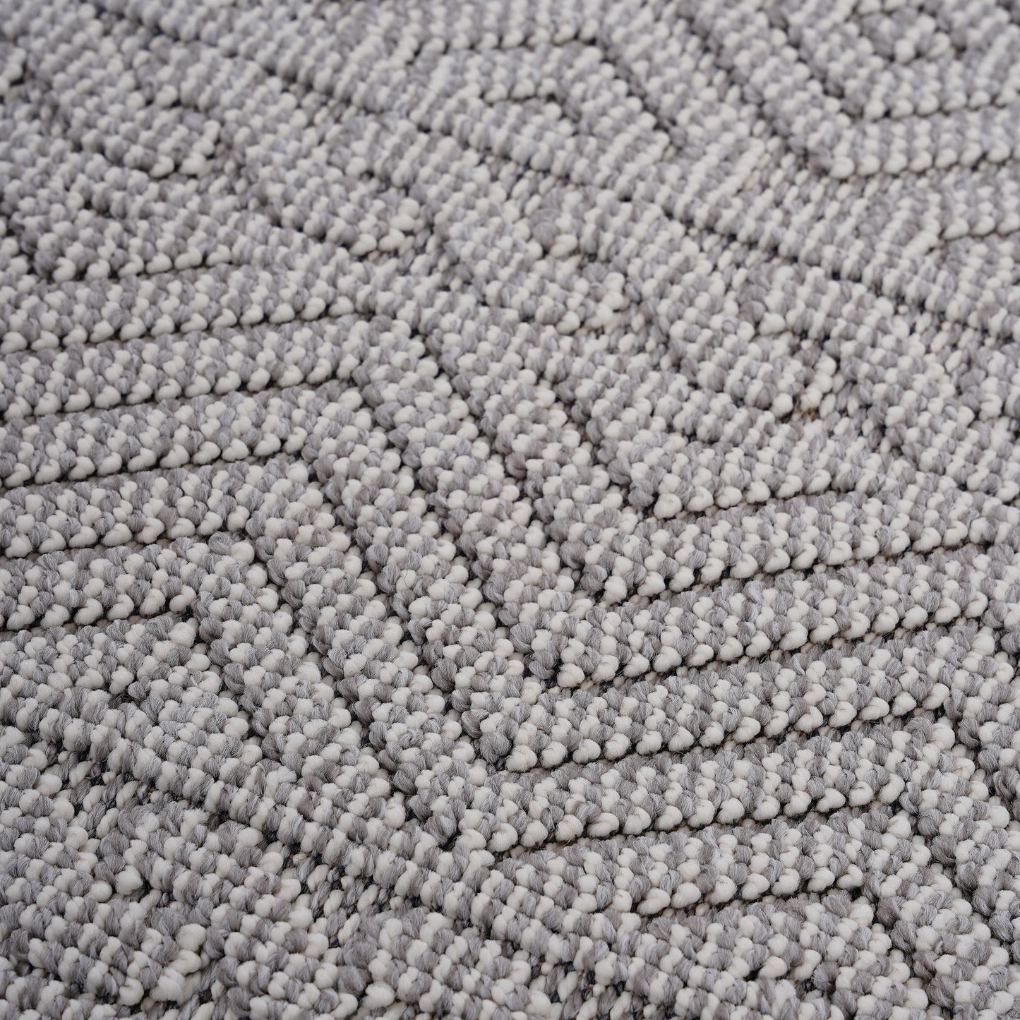 Closeup of textured grey and white woven rug with a geometric chevron pattern