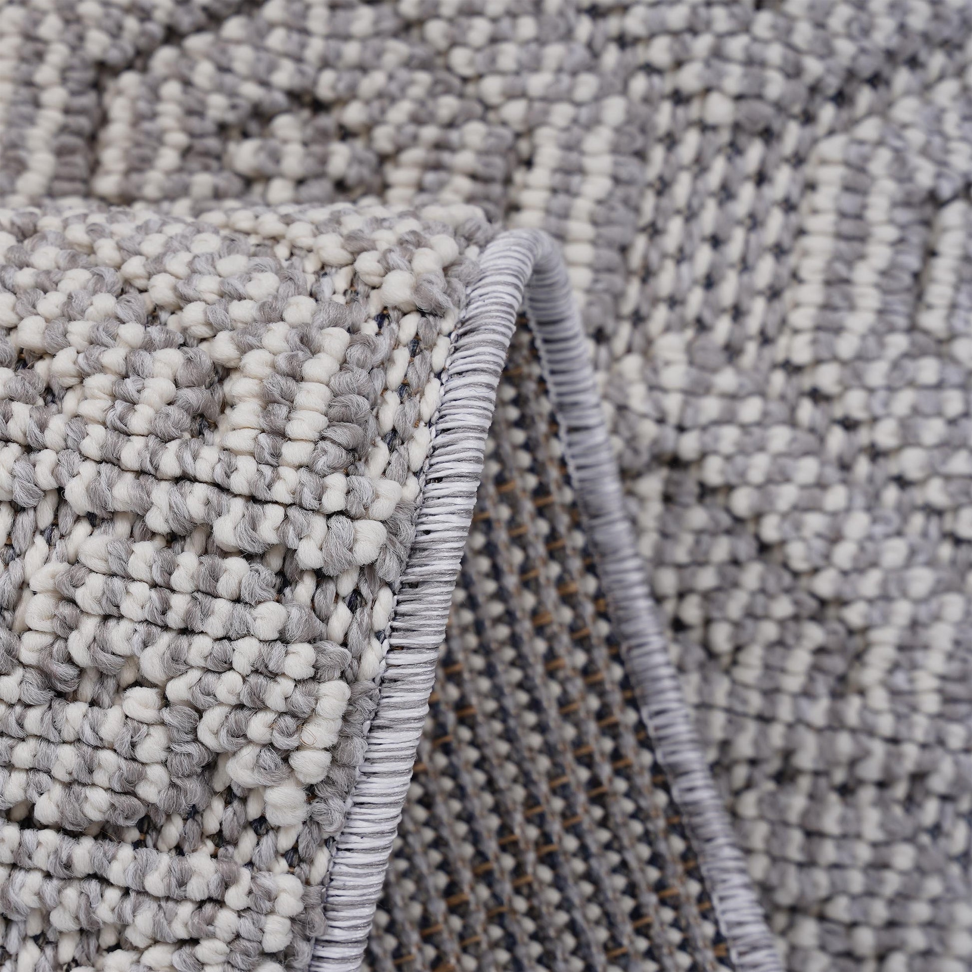 Closeup of a plush grey and white loop rug highlighting its textured woven pattern