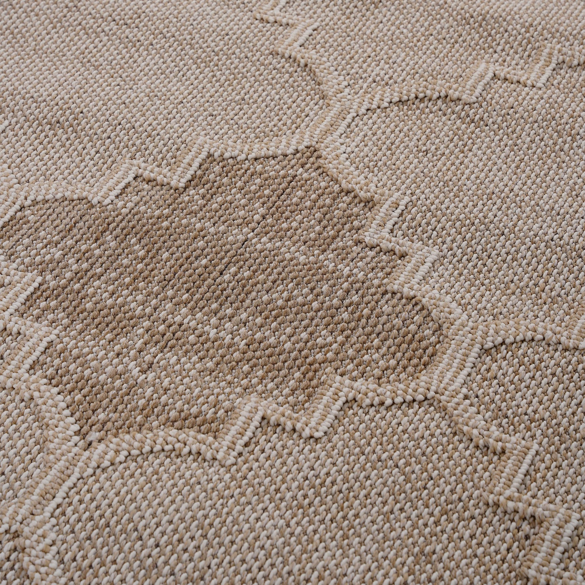 Closeup of a beige woven rug with a subtle diamond pattern texture