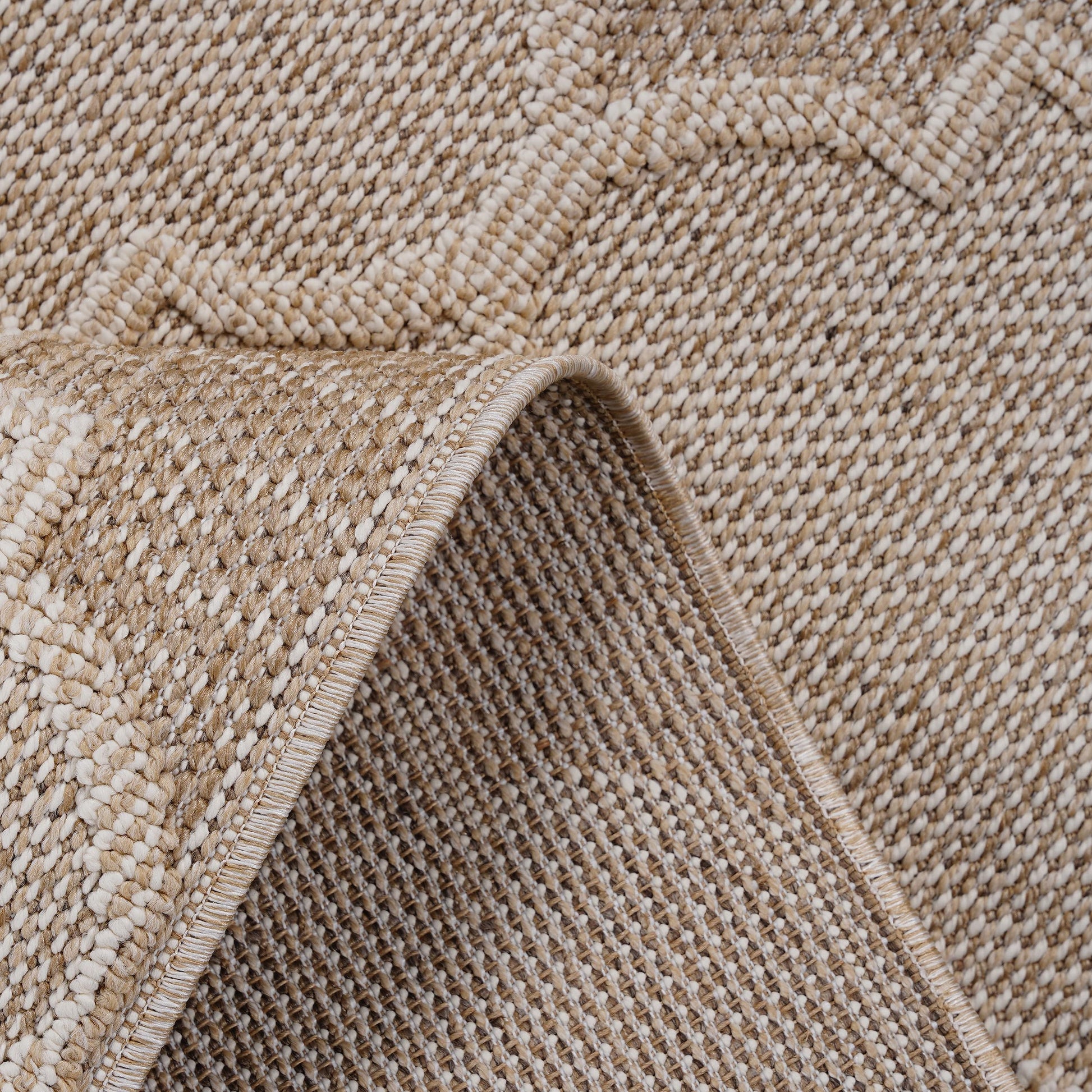 Closeup of a textured beige and cream woven rug with a subtle geometric pattern perfect for living rooms