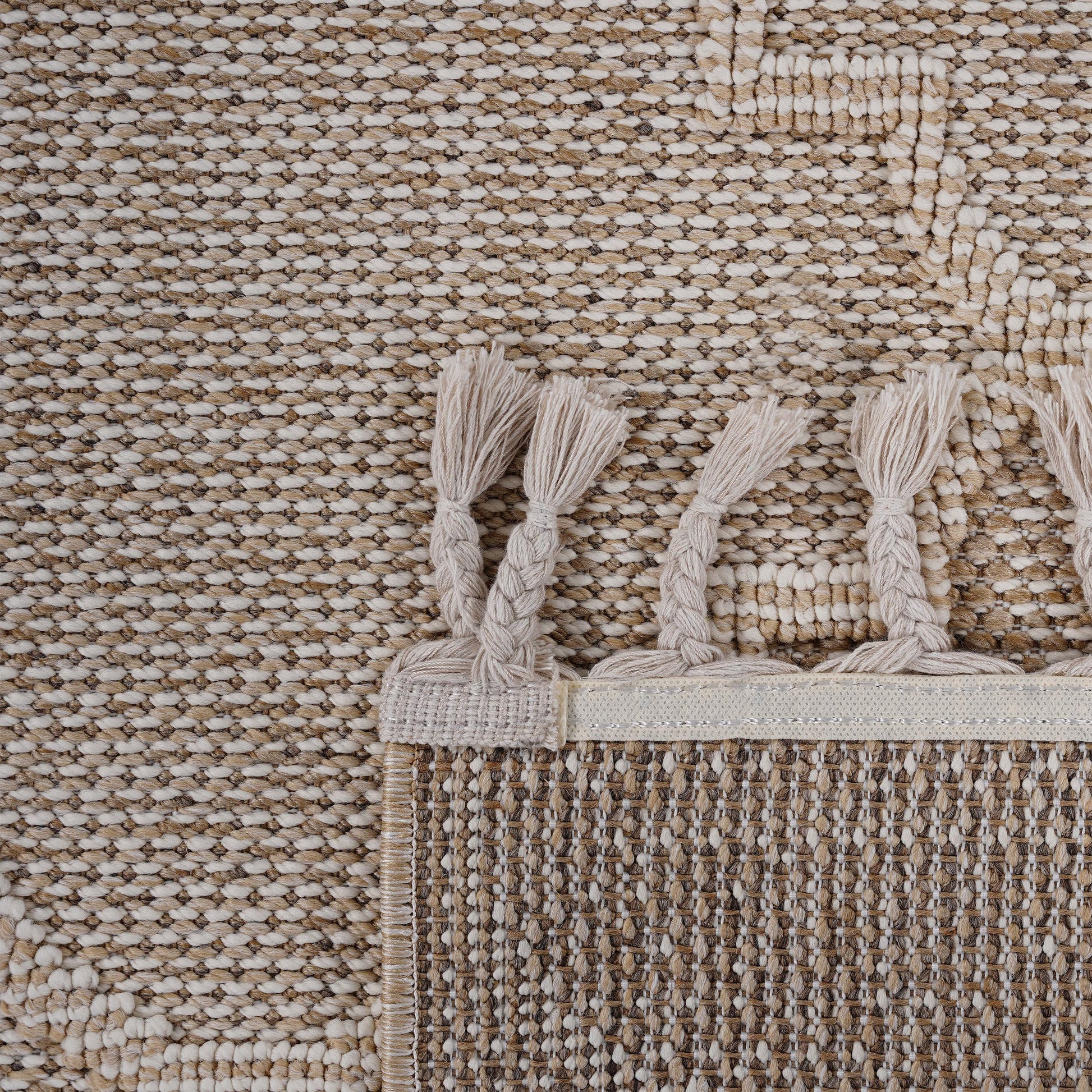 Closeup of a textured beige and white woven area rug with fringe details