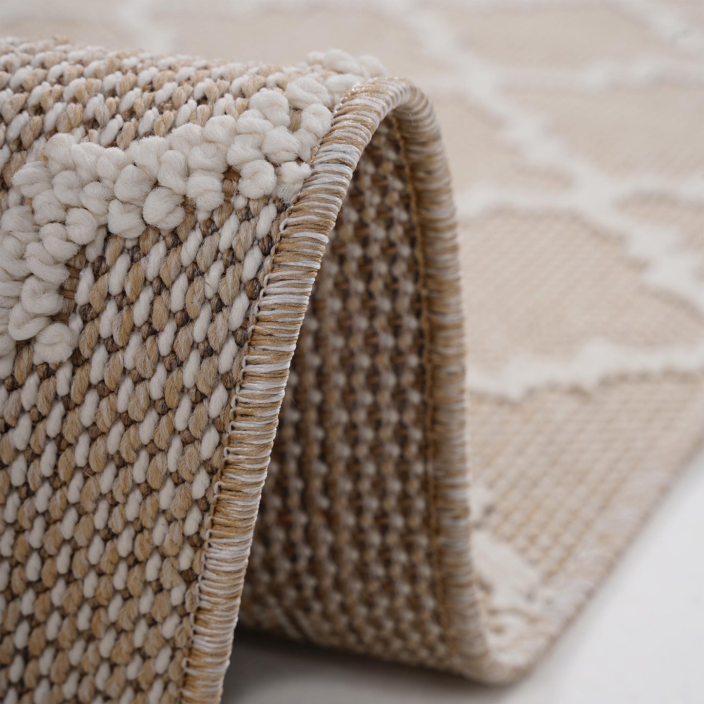 Closeup of textured beige area rug with raised looped pile and woven edges