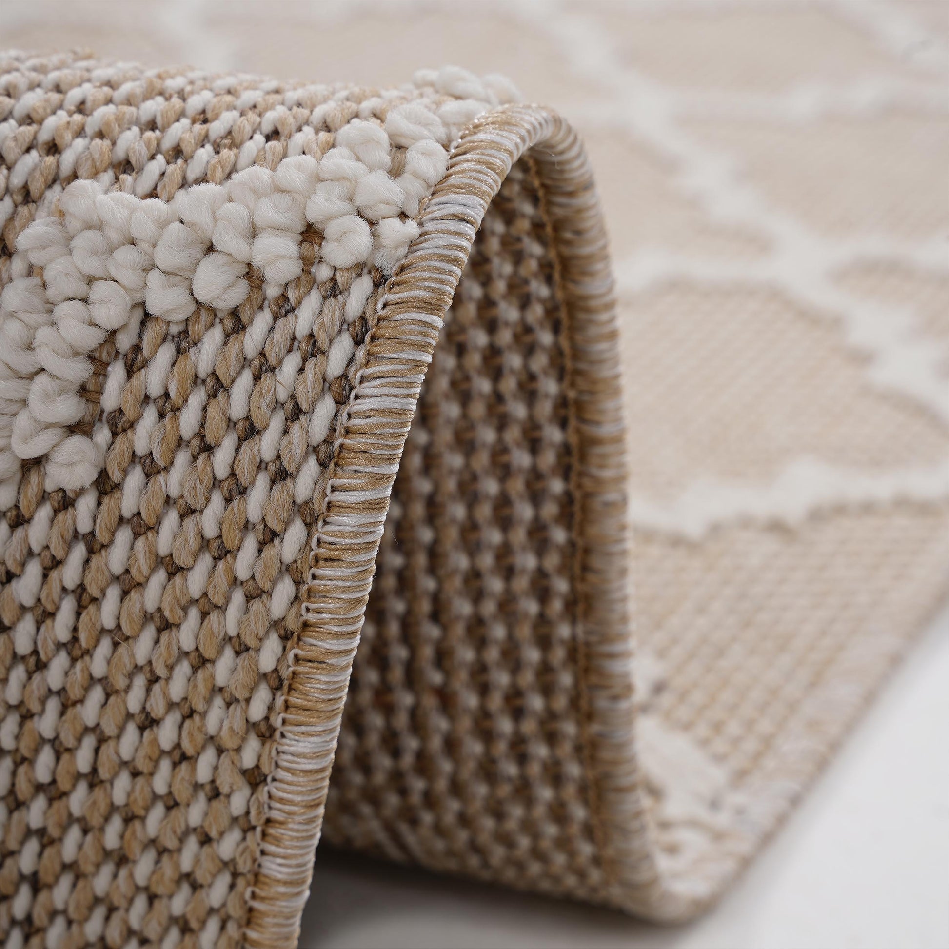 Closeup of textured beige area rug with raised looped pile and woven edges