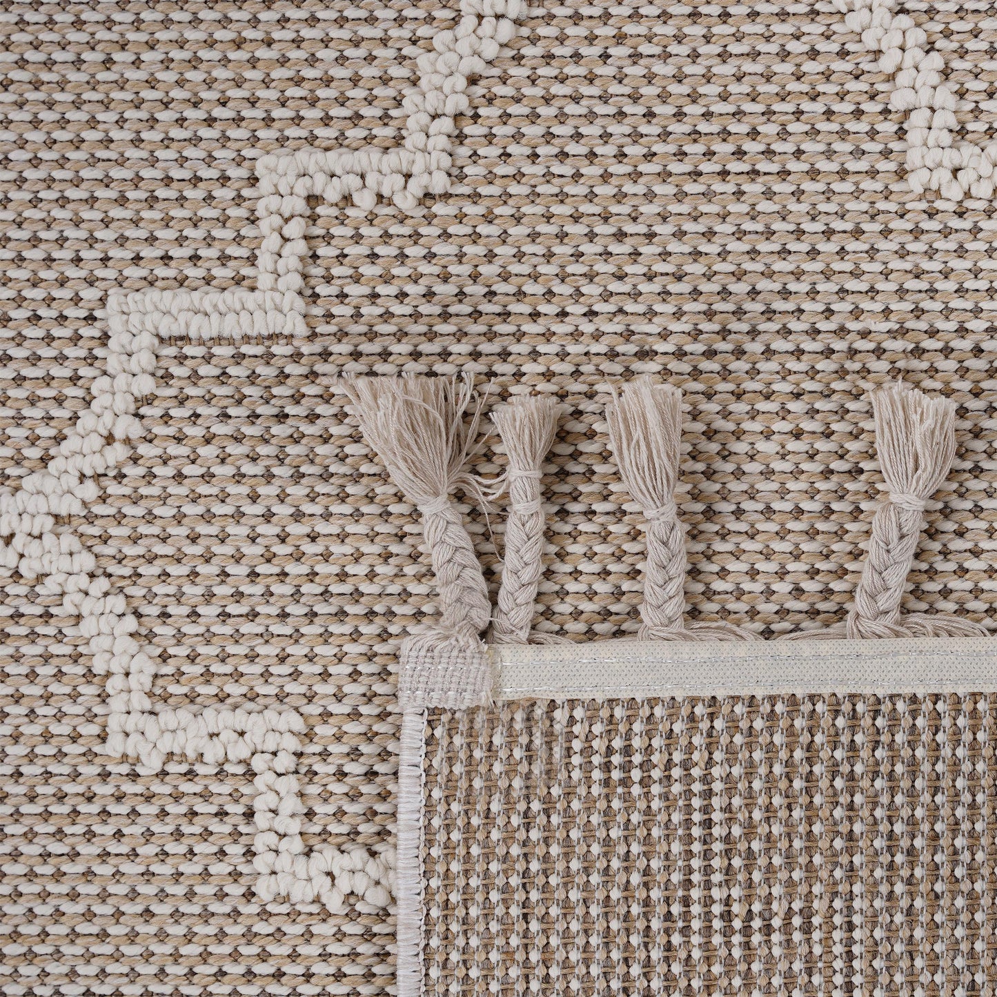 Textured beige and cream woven rug with braided tassels and a geometric pattern