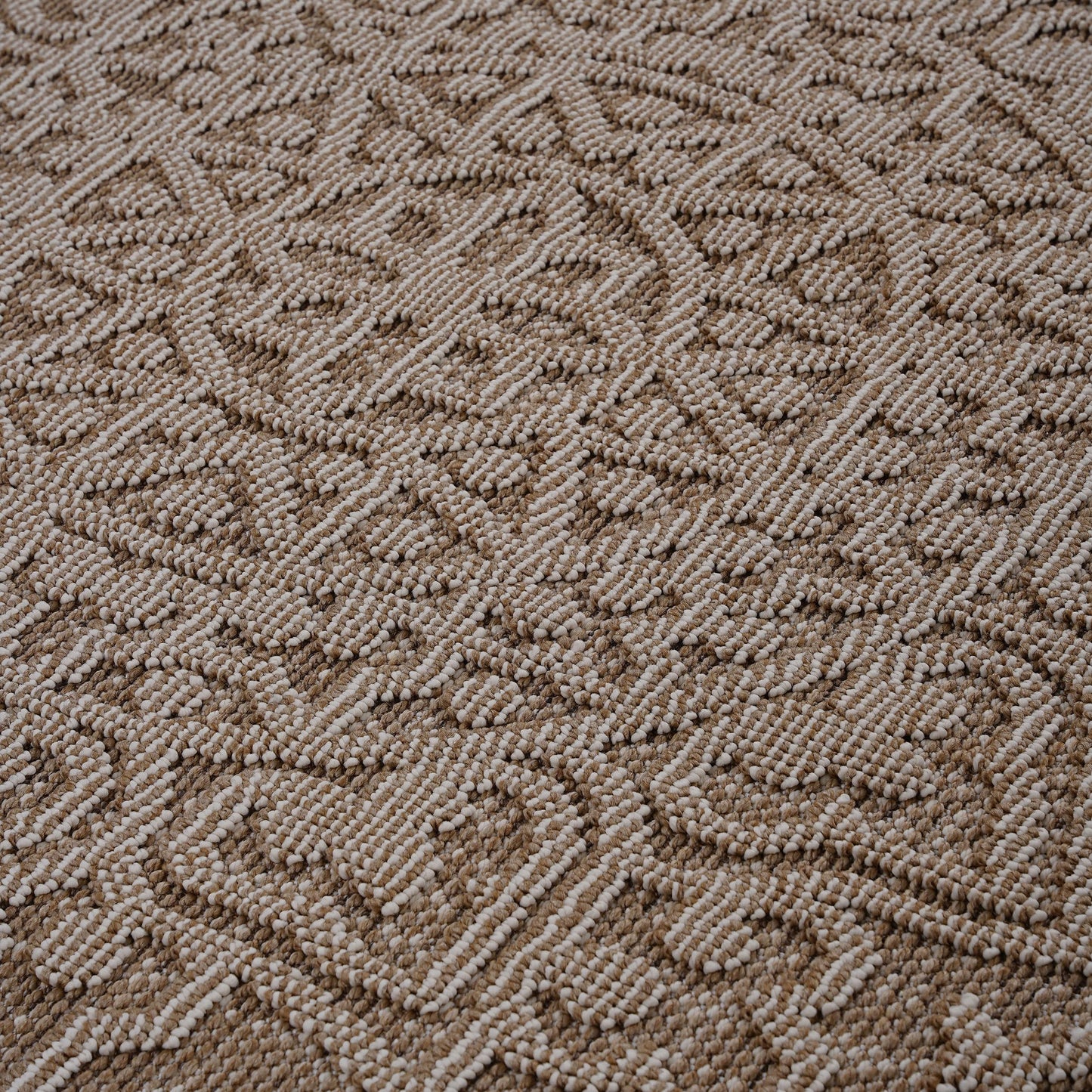 Closeup of a textured beige and white looped area rug with a geometric diamond pattern